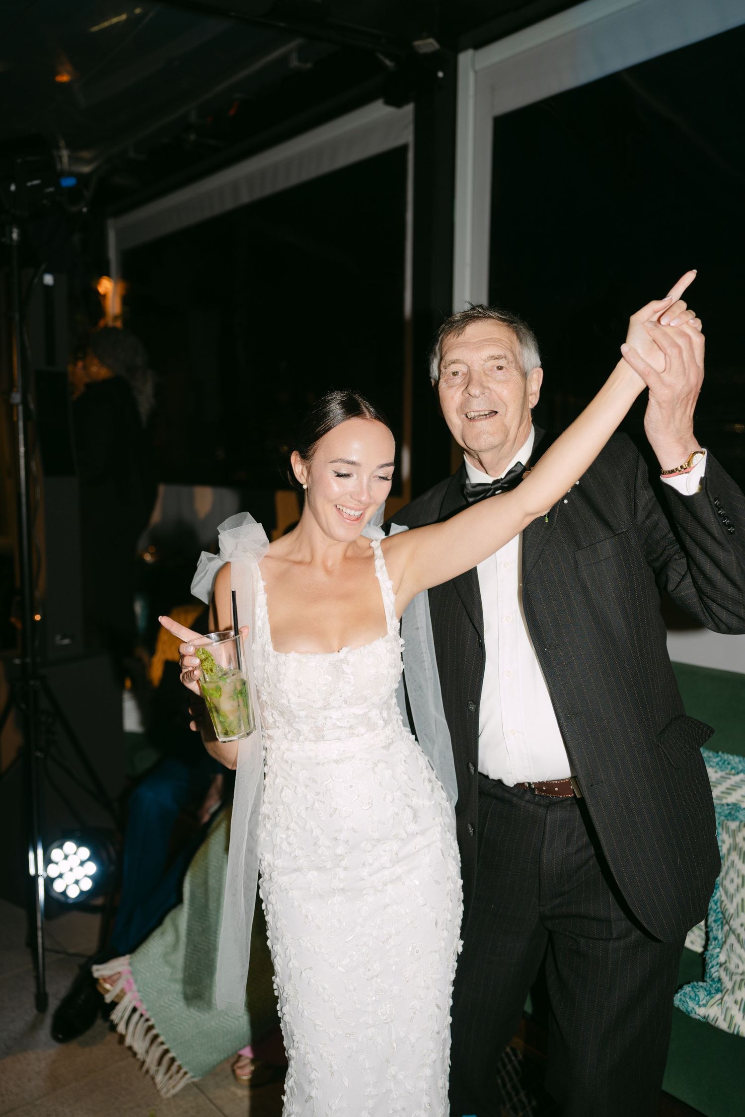 Wedding celebration with enthusiastic dancing on dark dance floor.