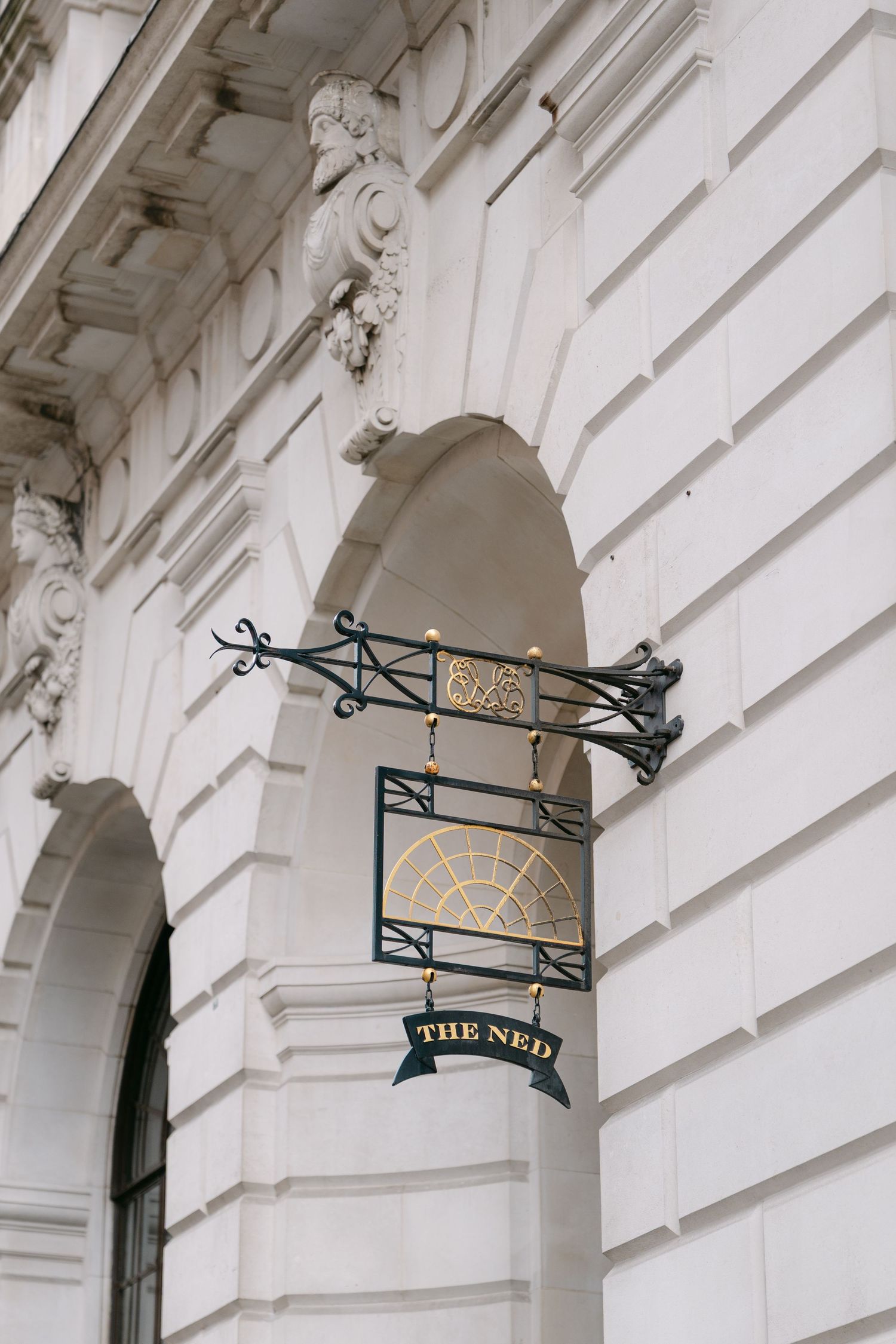 Ornate white architectural details with decorative iron signage reading 'The Ned'.