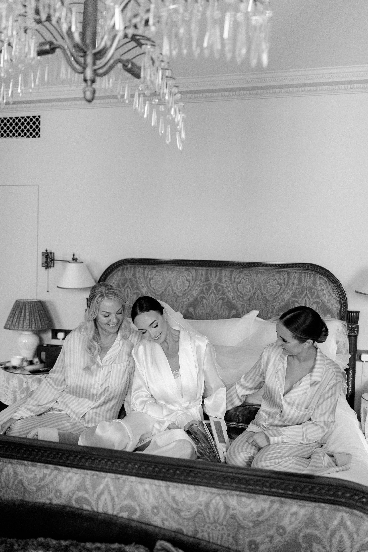 Group lounging on ornate couch under crystal chandelier wearing matching striped pajamas.