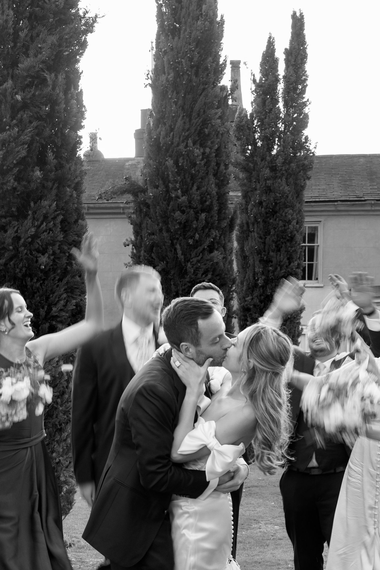 Black and white sequence of wedding party toasting and celebrating outdoors.