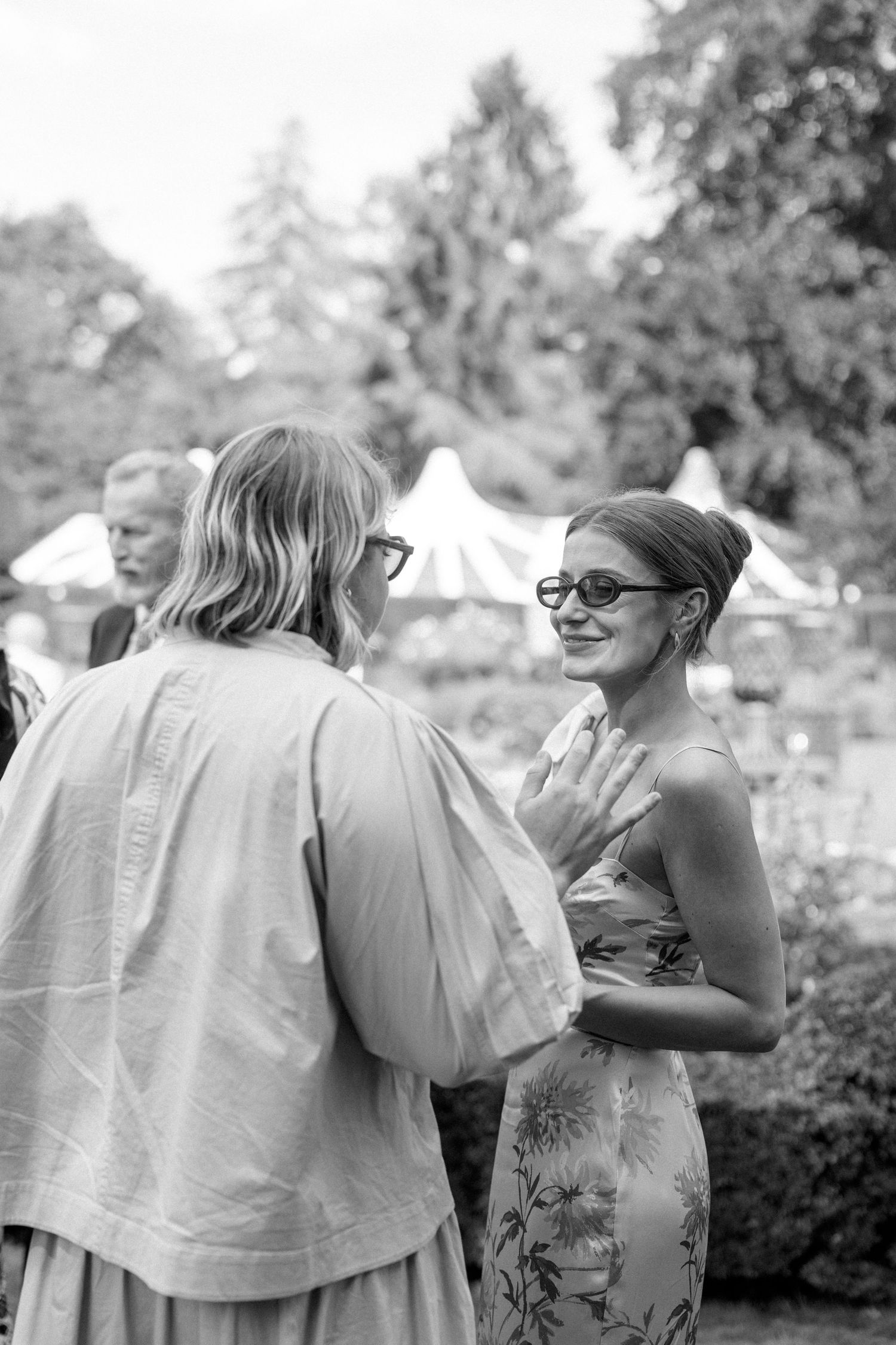 Guests engage in animated conversation during an elegant outdoor summer gathering.