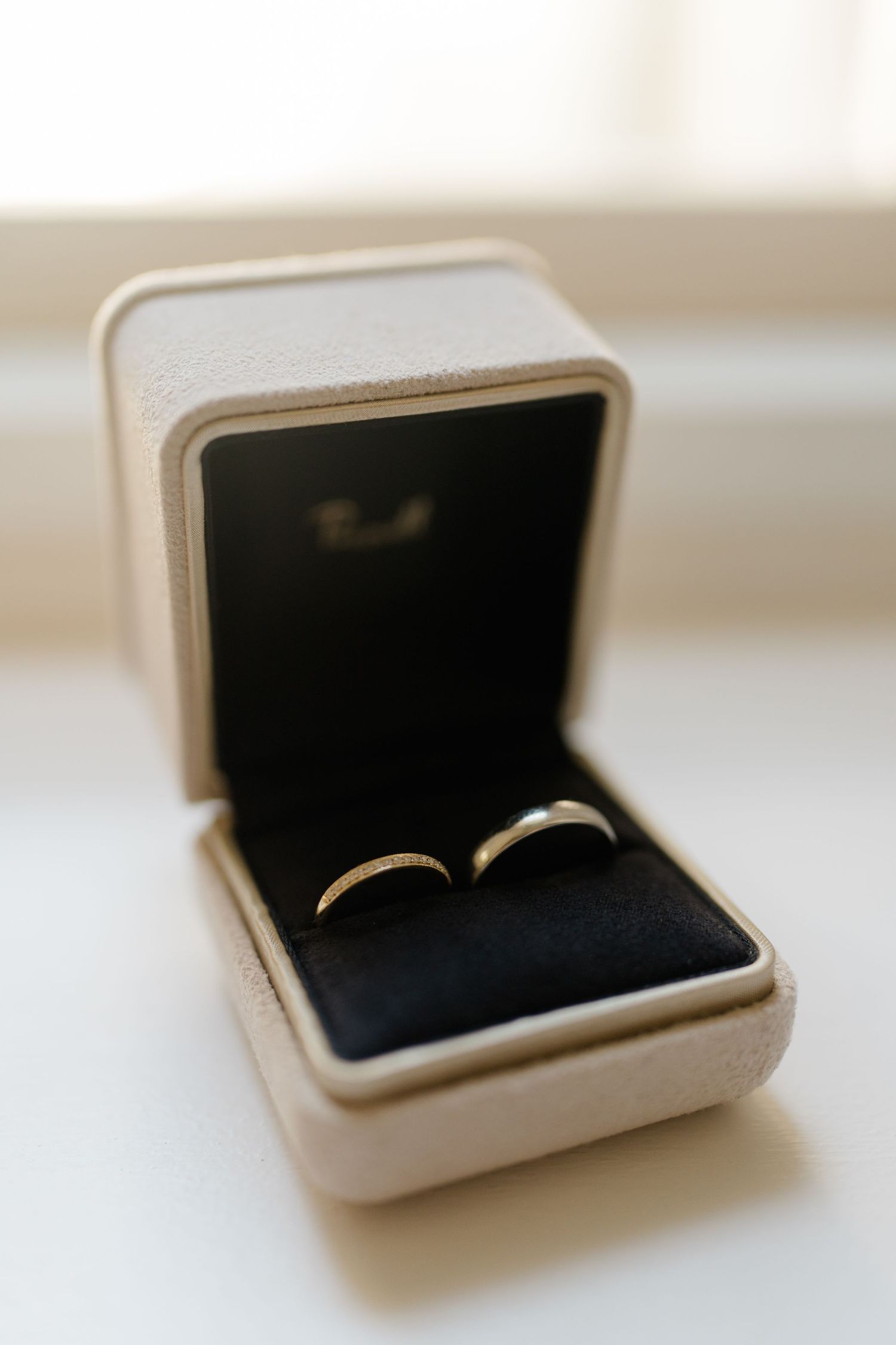 Two silver wedding bands displayed in an open white velvet ring box with dark interior lining.