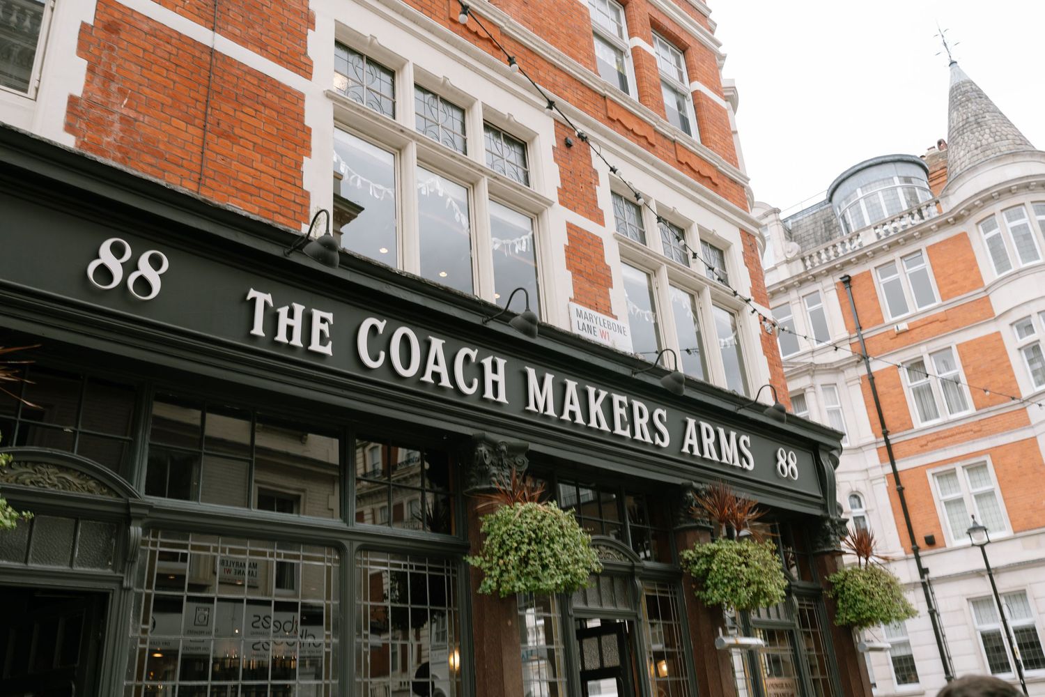 A row of classic brick buildings with storefronts including The Coach Makers Arms pub.