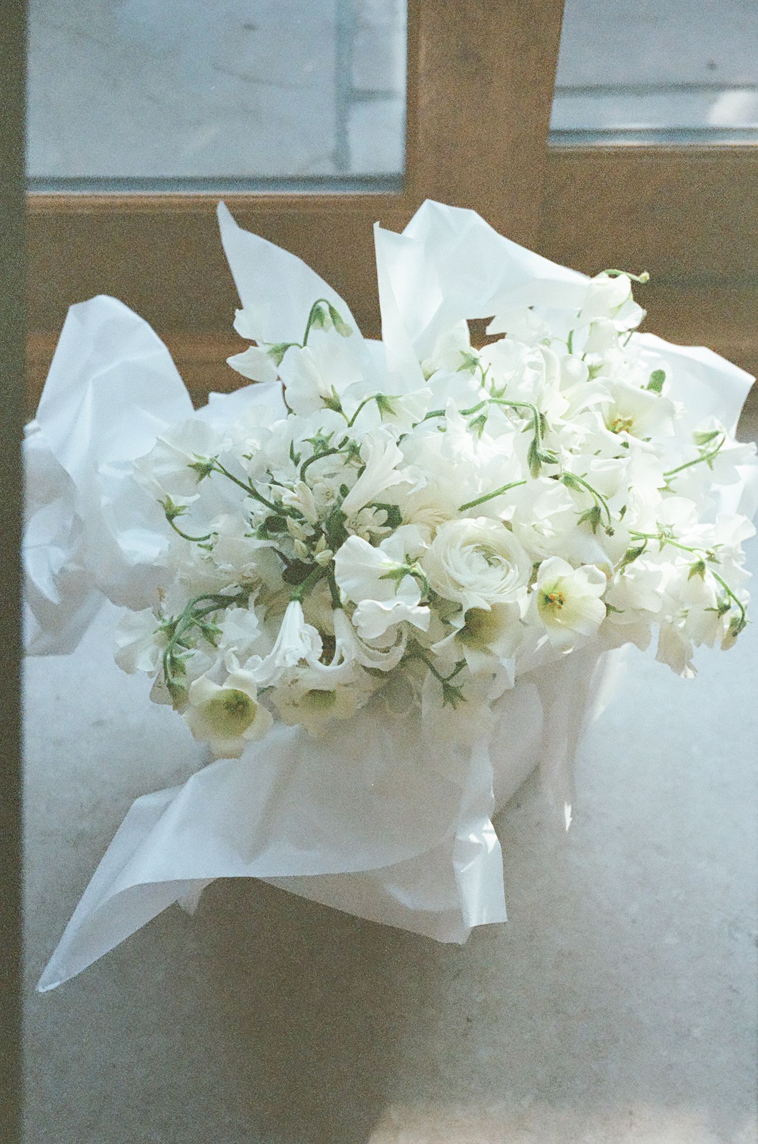 A delicate garland of white flowers and tissue paper decorates a window ledge in soft natural light.