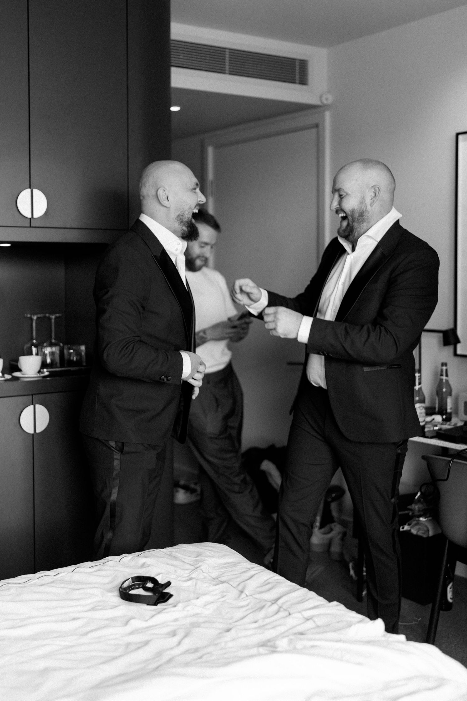 Black and white photo of groomsmen getting ready in formal attire.