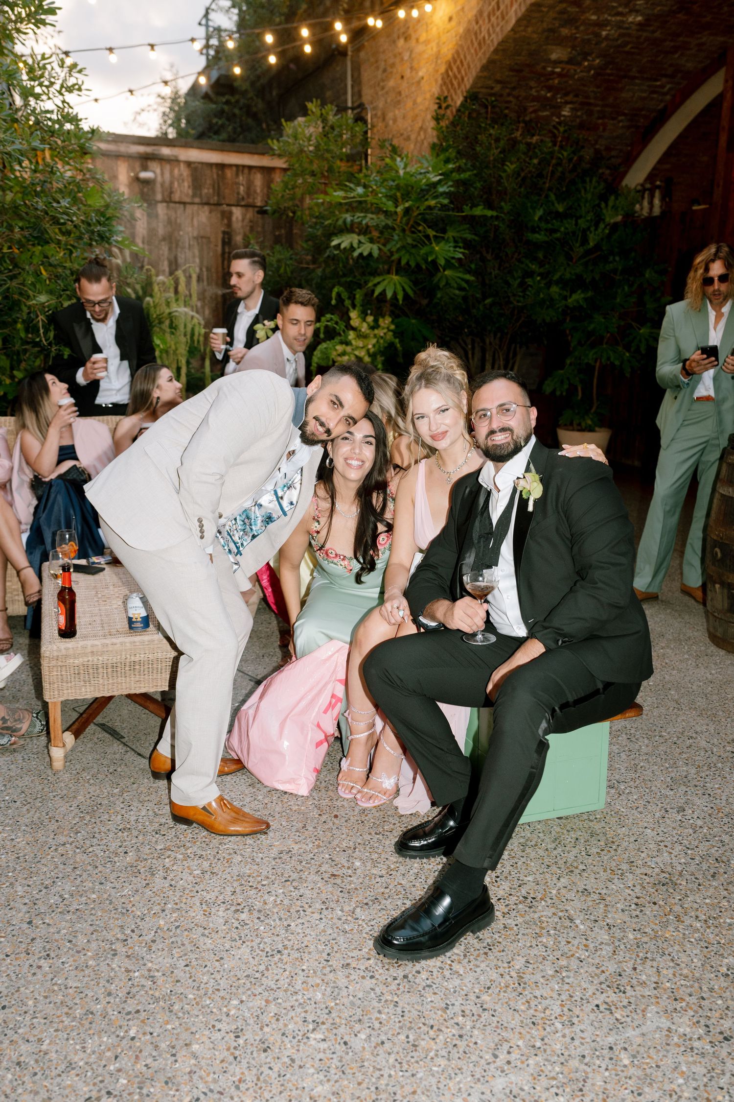 Wedding guests enjoying casual moments on the ground at an outdoor reception.