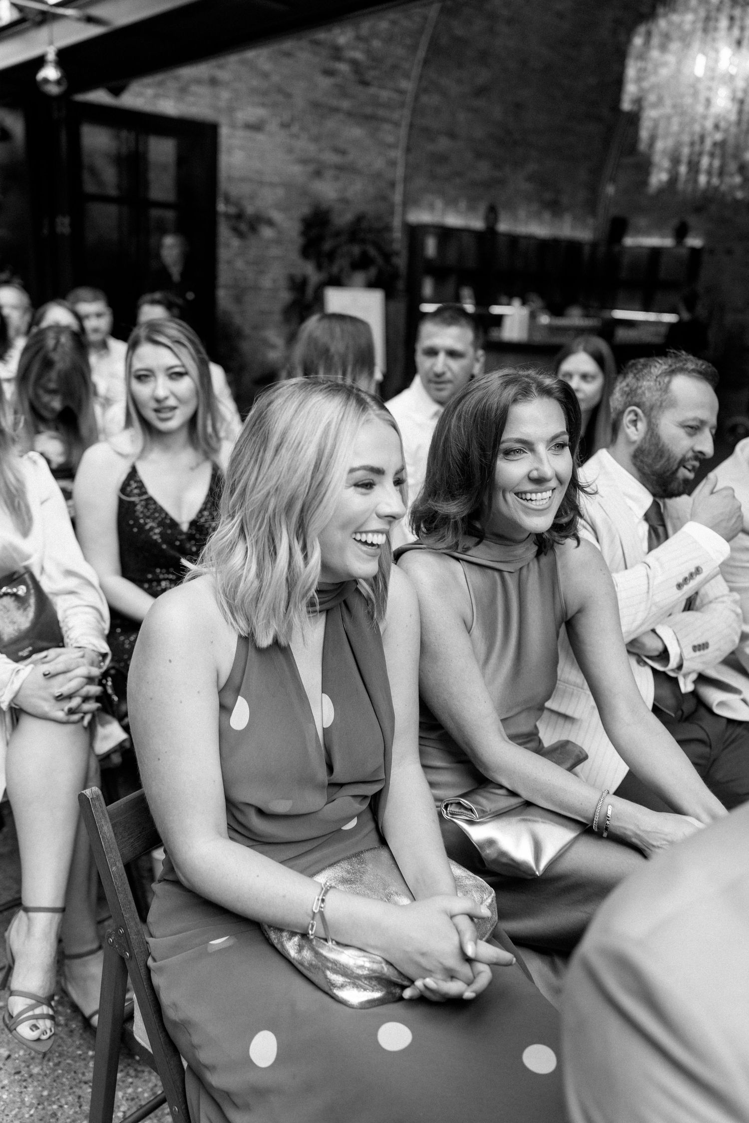 Wedding guests seated at a long table share joyful moments during the reception celebration.