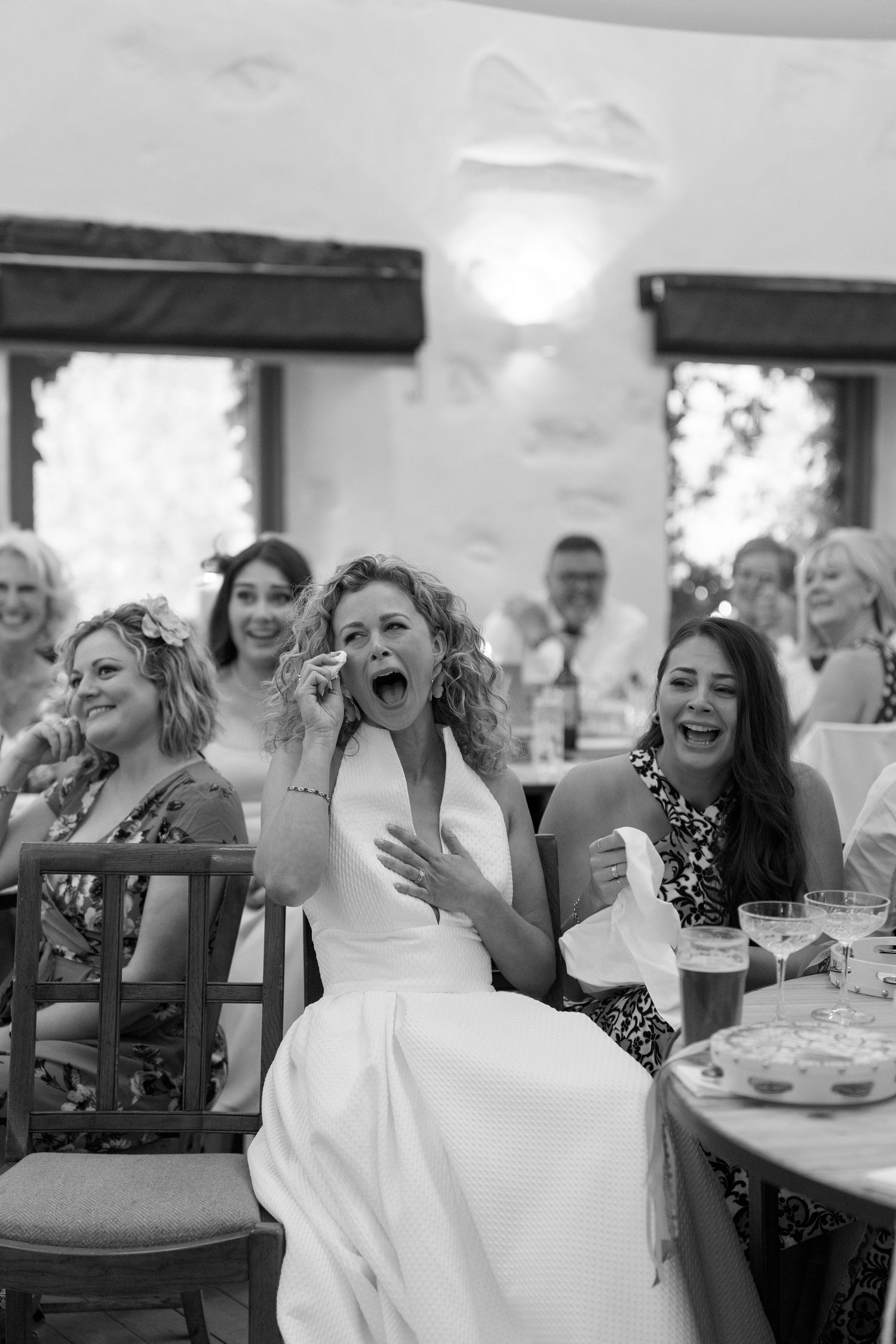 Wedding reception guests laughing and enjoying celebration at tables.