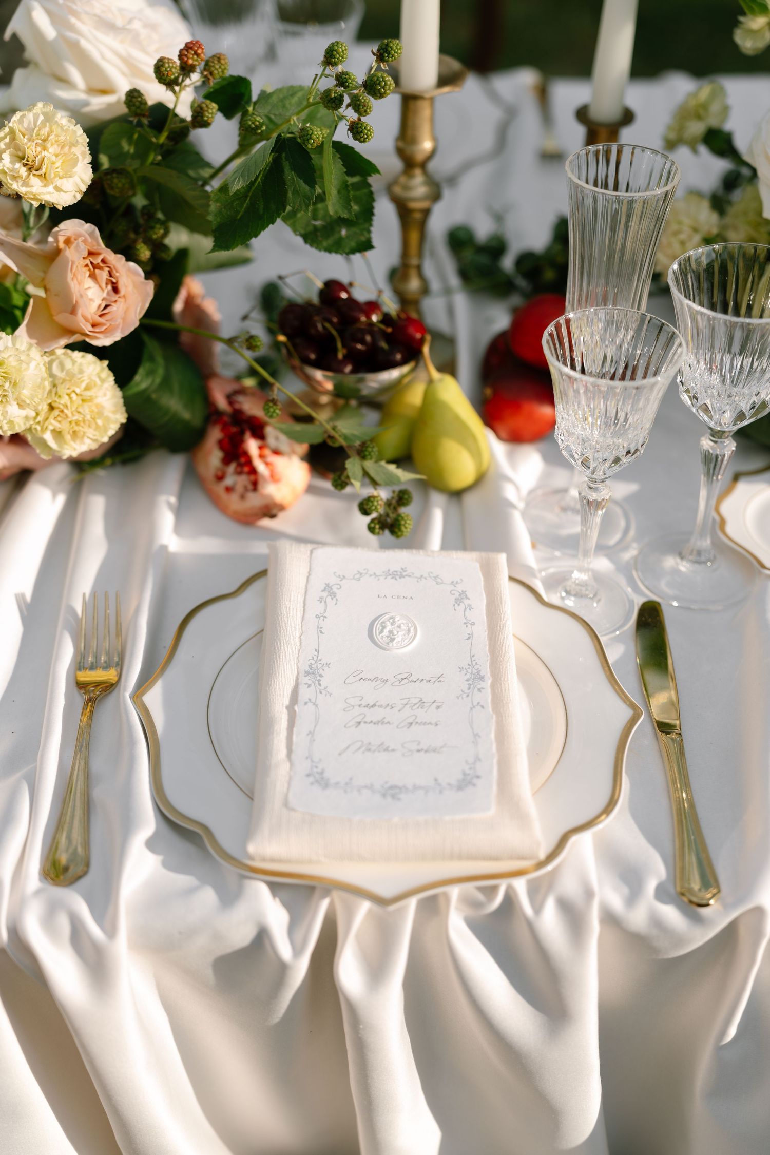 Elegant white table setting with crystal glasses, floral arrangements, and decorative place cards for a formal event.