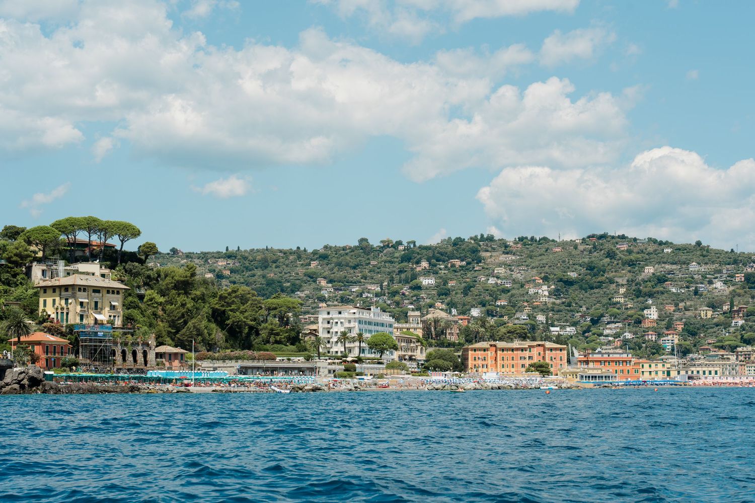 Scenic coastal Italian town with colorful buildings on hillside overlooking blue Mediterranean sea.