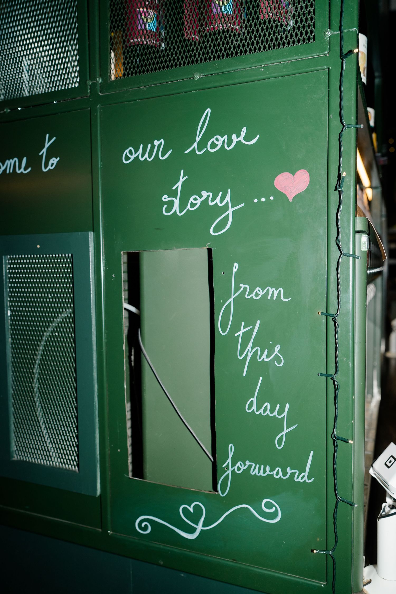 Green chalkboard sign reading our love story from this day forward with heart decoration at wedding venue.