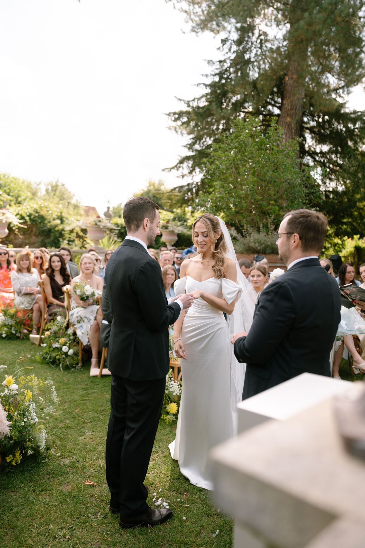 Wedding couple dances together on a grassy lawn surrounded by guests.