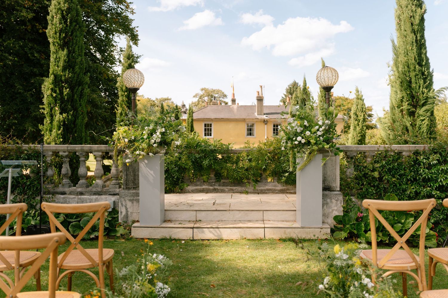 Panoramic view of a grand garden venue with stone balustrades and cypress trees.
