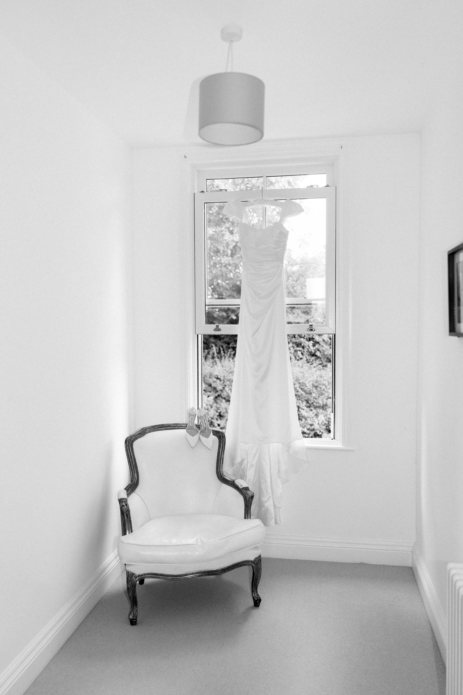 Minimalist white room interior with vintage chair and window creating bright, airy atmosphere.