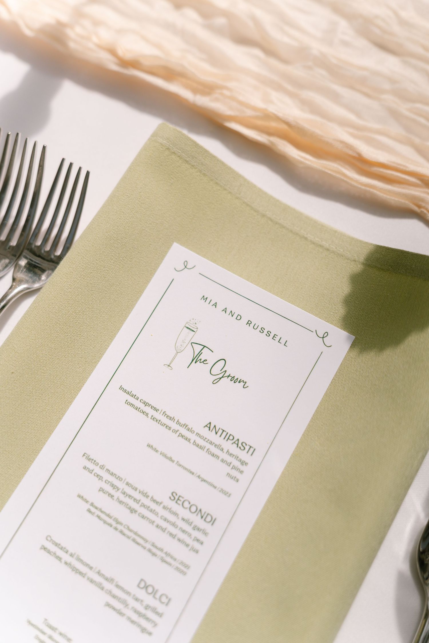 Wedding menu cards with elegant typography displayed alongside silver cutlery.
