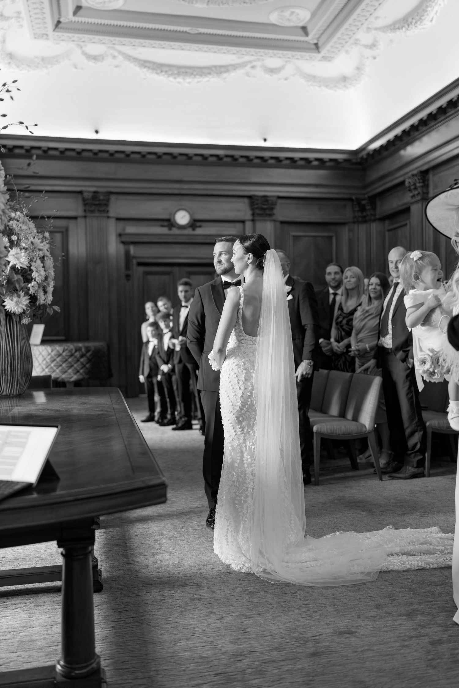 Wedding ceremony in an elegant room with wood paneling and decorative ceiling details.