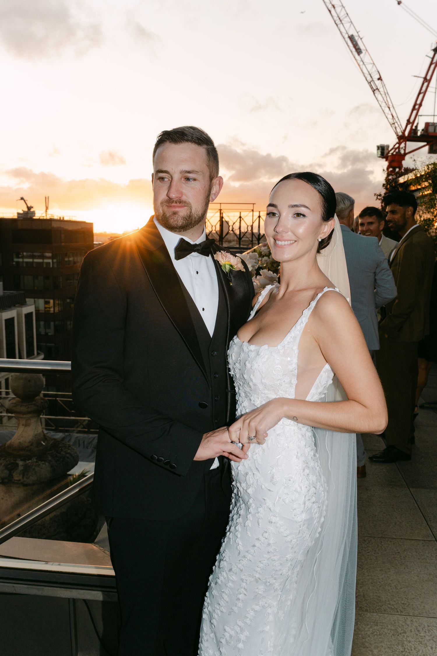 Candid wedding moments captured on rooftop with sunset city views.