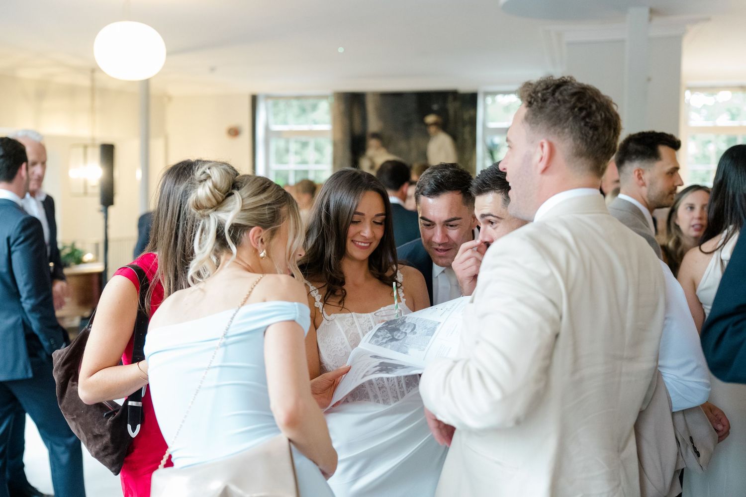 Wedding guests gather and mingle indoors at a bright, modern wedding reception venue.