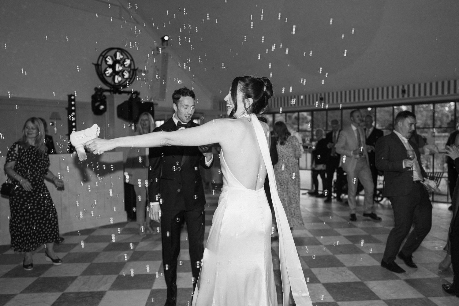 Bride and groom share first dance surrounded by confetti on the dance floor, black and white photo.