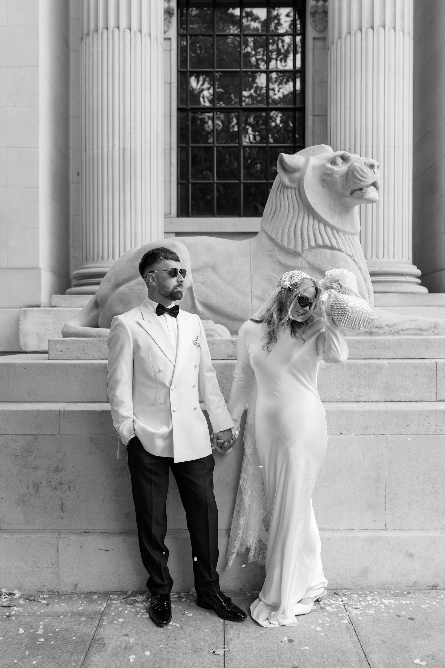A black and white wedding photo series featuring elegant poses against classical columns.