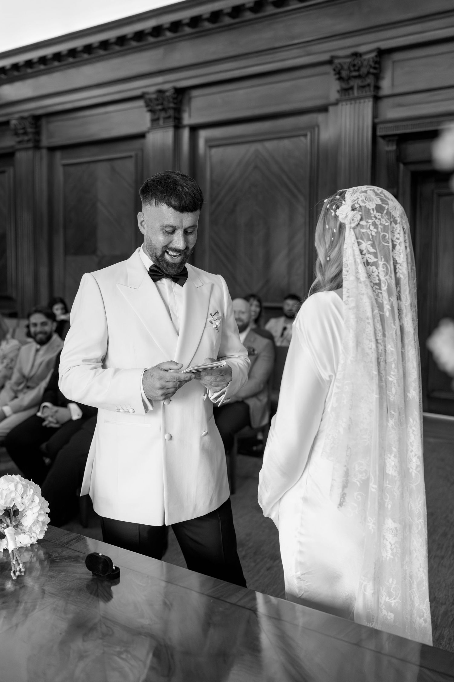 A couple exchanges vows during an intimate ceremony in an elegant wood-paneled room.