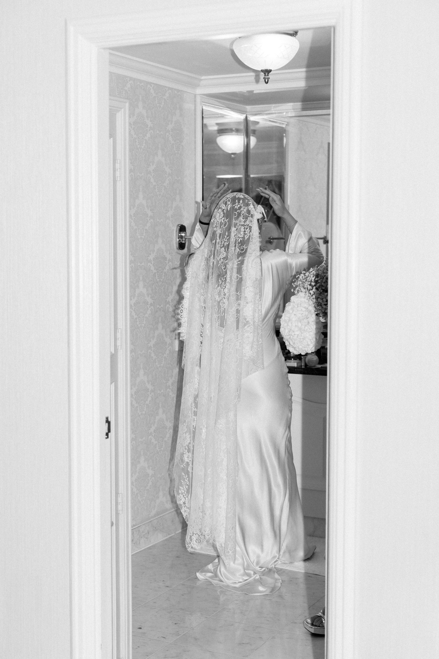 Wedding dresses hanging in a bright hallway with white walls and elegant lighting.