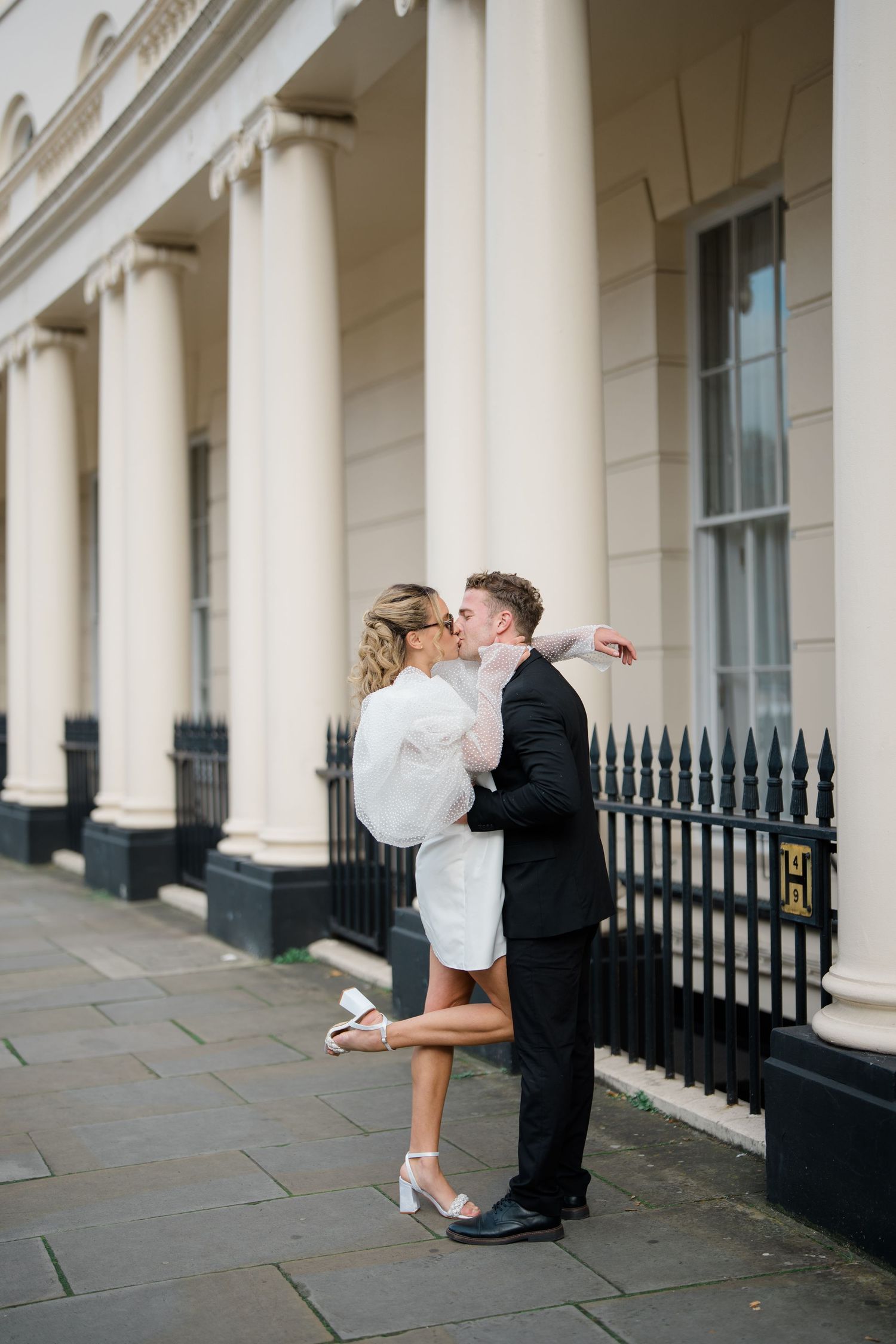 A romantic moment captured under classic white columns and iron railings.