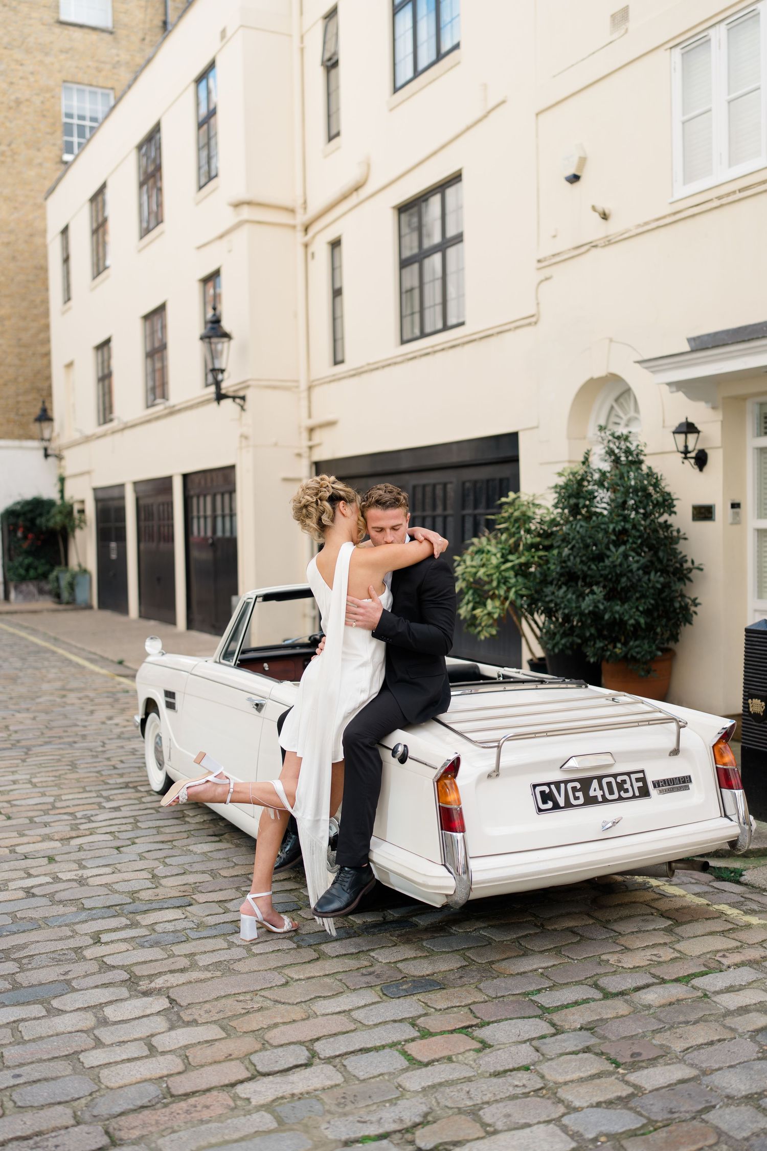 A romantic photoshoot with a classic white car on a European cobblestone street.