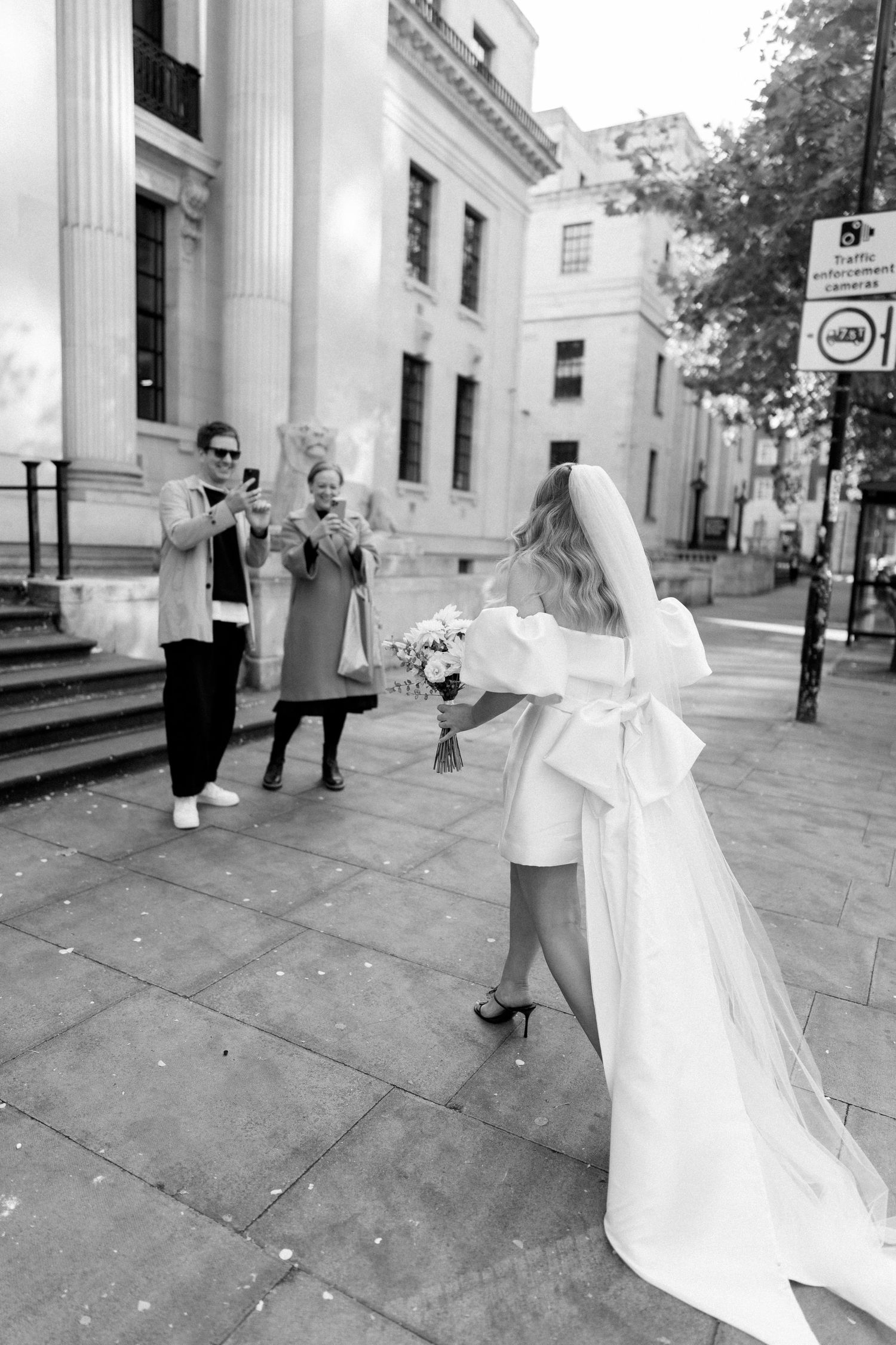 Black and white wedding photos taken outside historic building with columns.