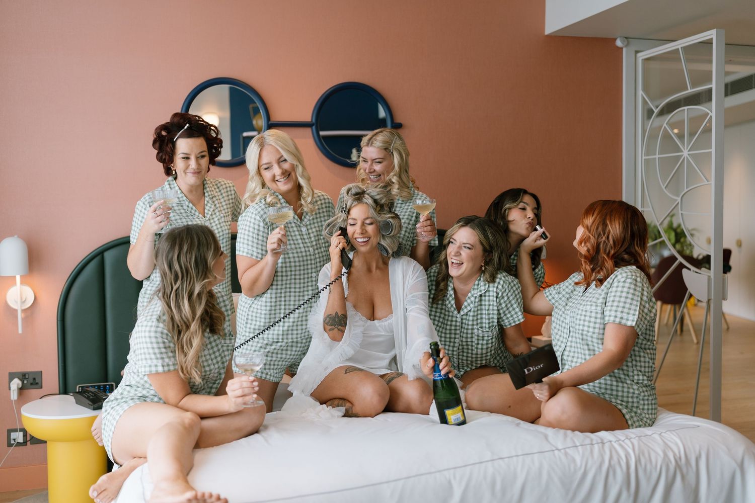 Wedding party in matching outfits relaxing and celebrating on a bed together.