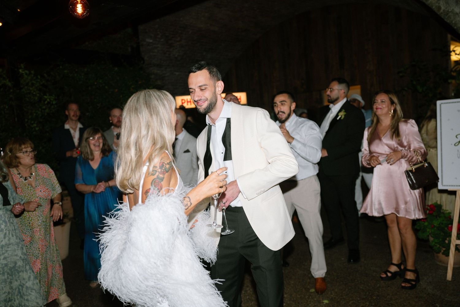 Wedding celebration dance sequence showing guests moving on a dimly lit dance floor.
