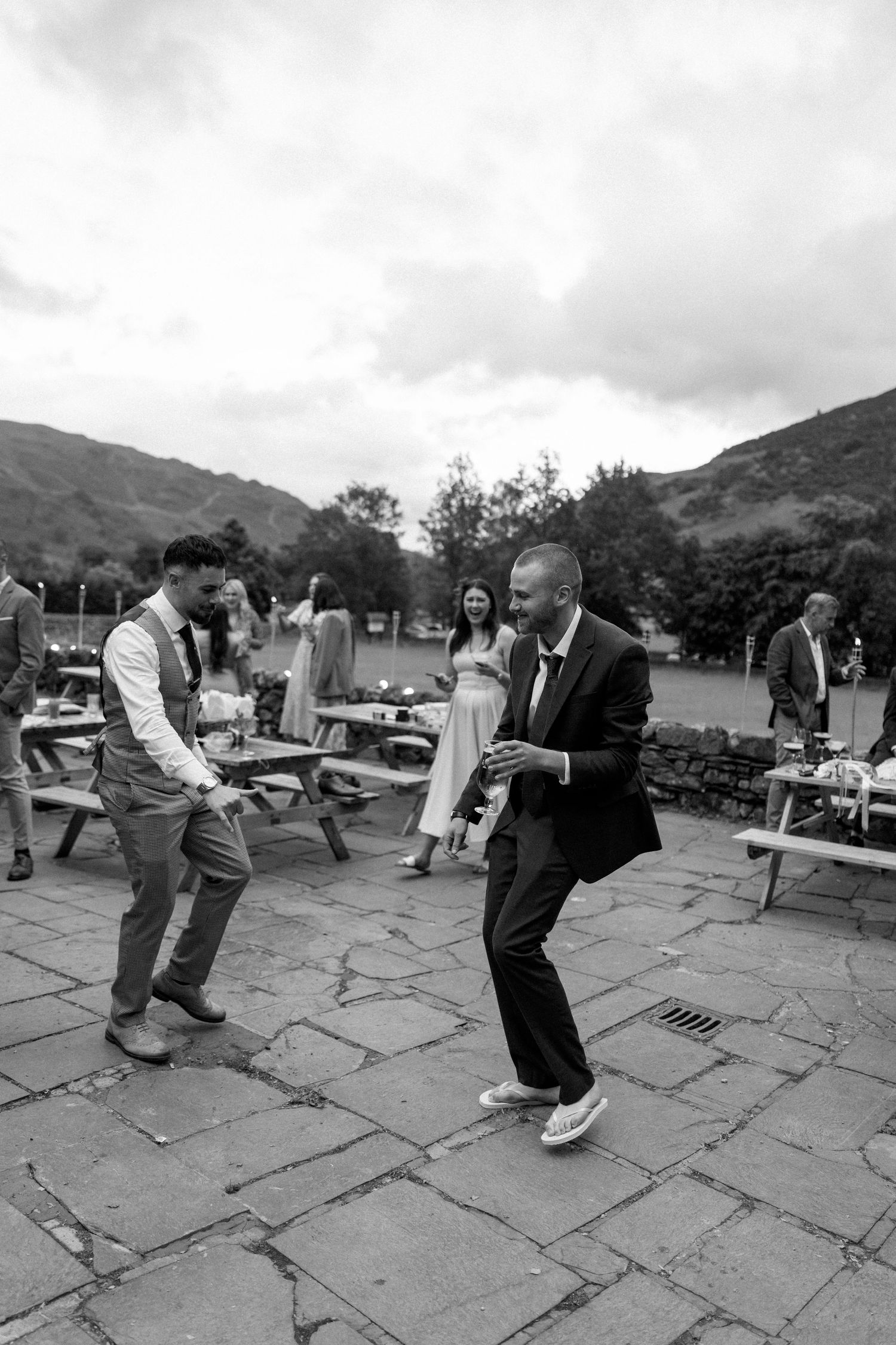 Black and white sequence of wedding guests dancing on stone patio.