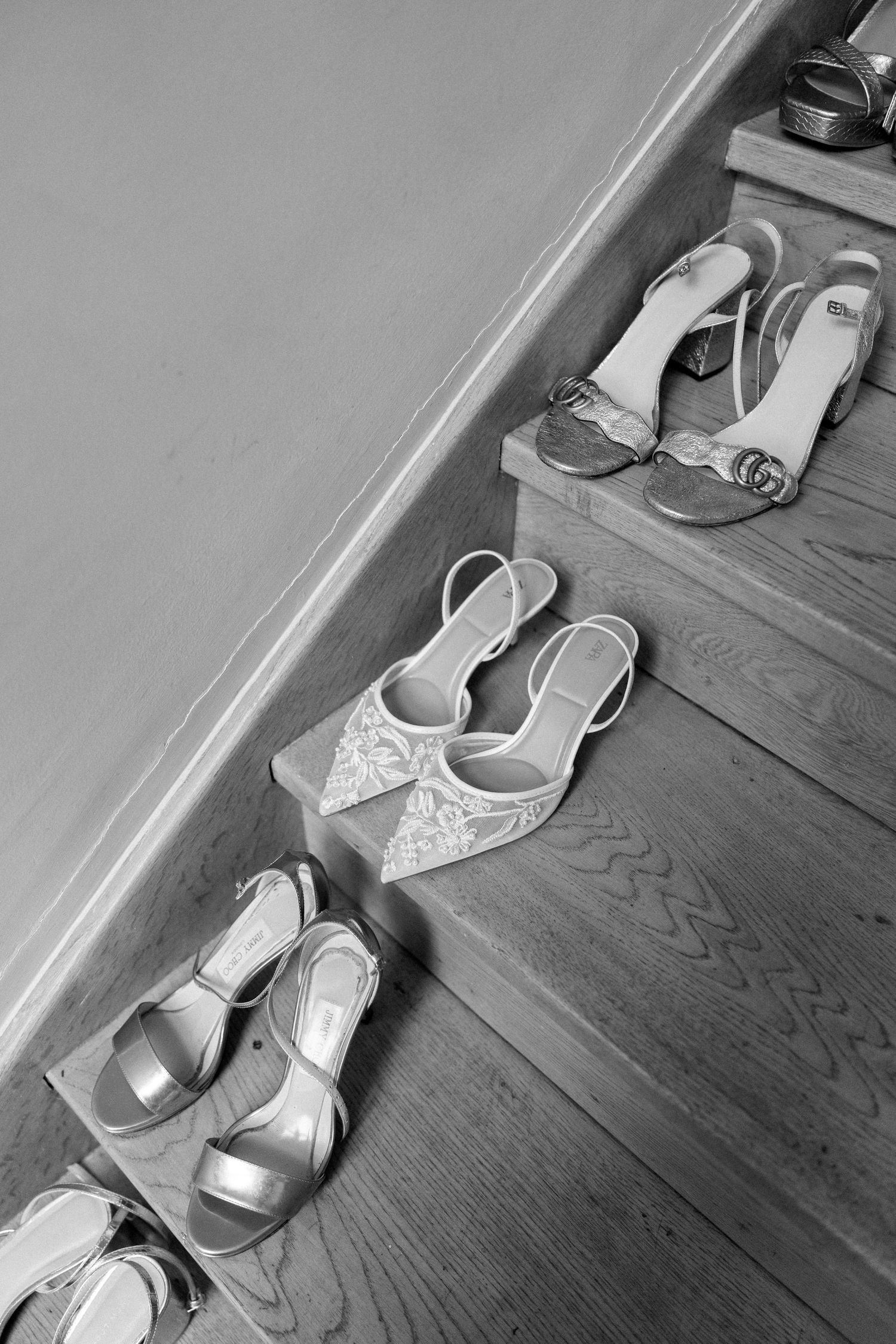 A sequence of white bridal shoes arranged on a dark wooden floor.