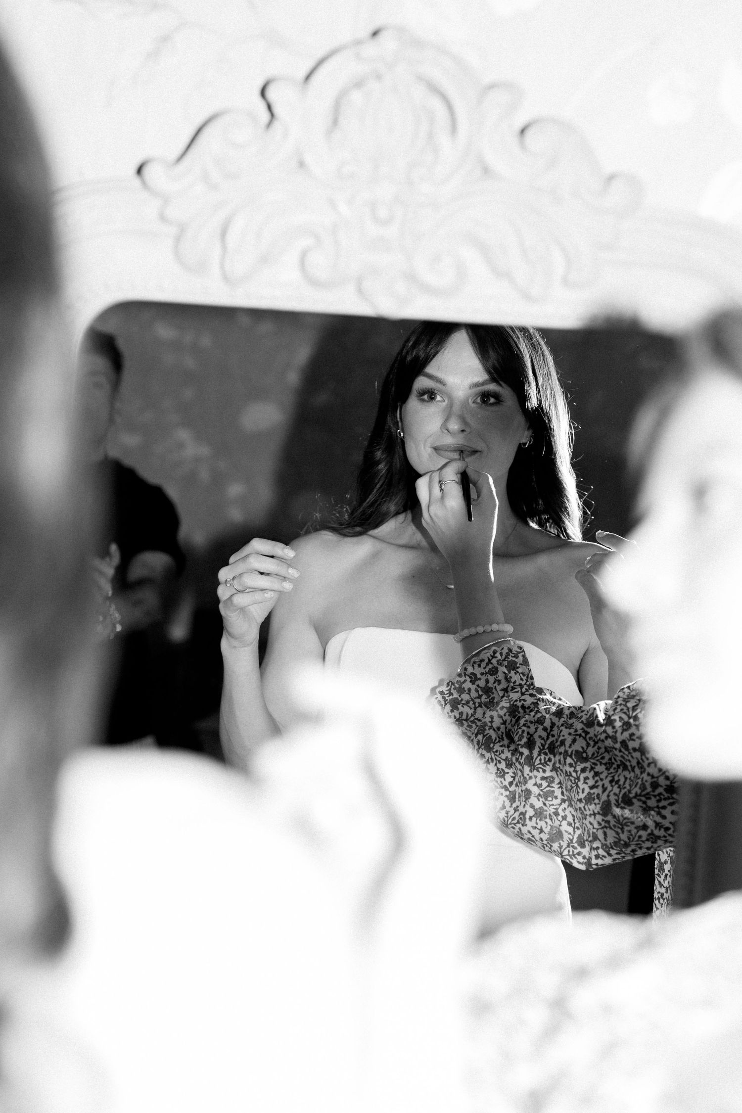A reflection captured in an ornate mirror shows a bride making final wedding day preparations.