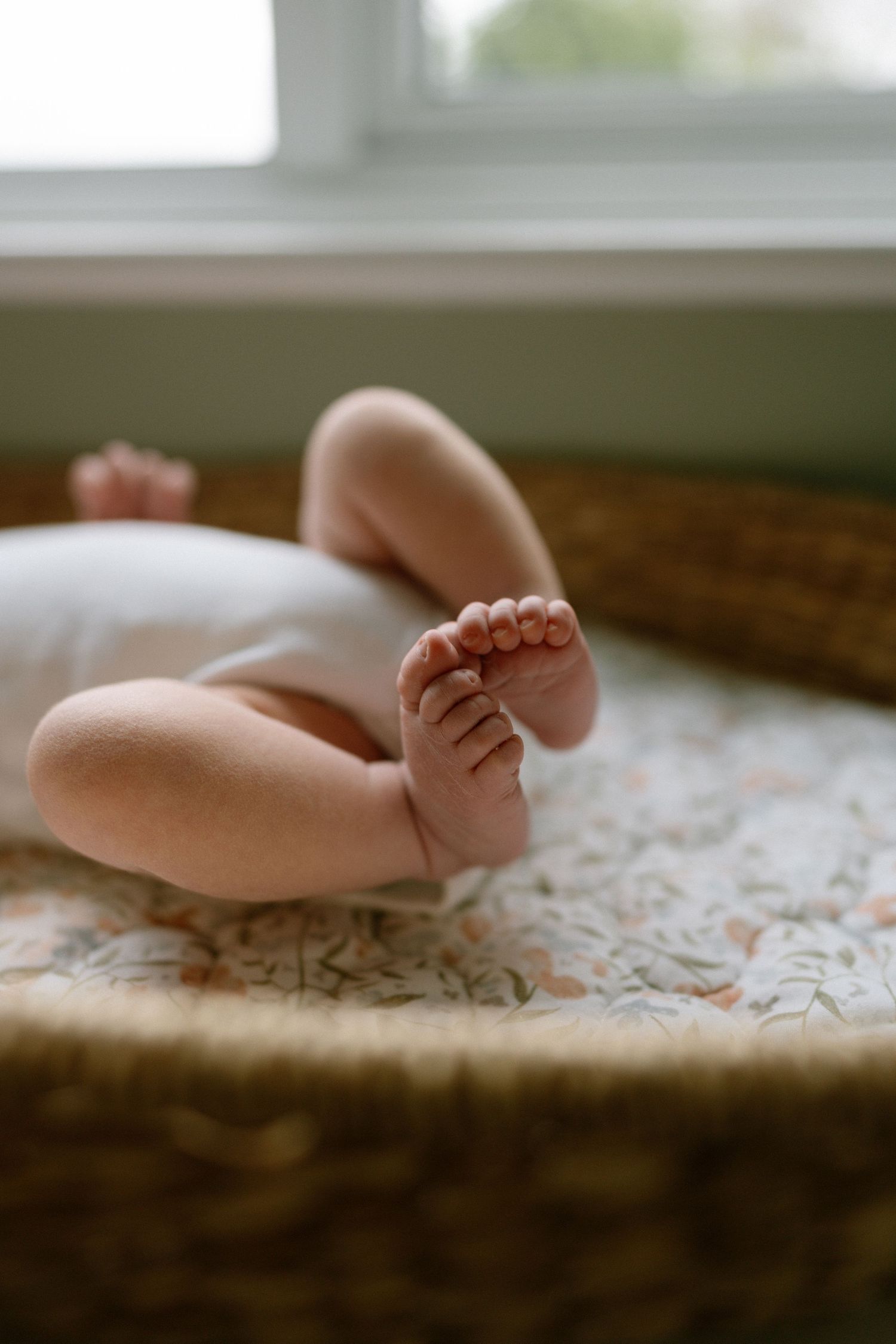 Close-up of tiny newborn baby feet resting on a floral patterned blanket.