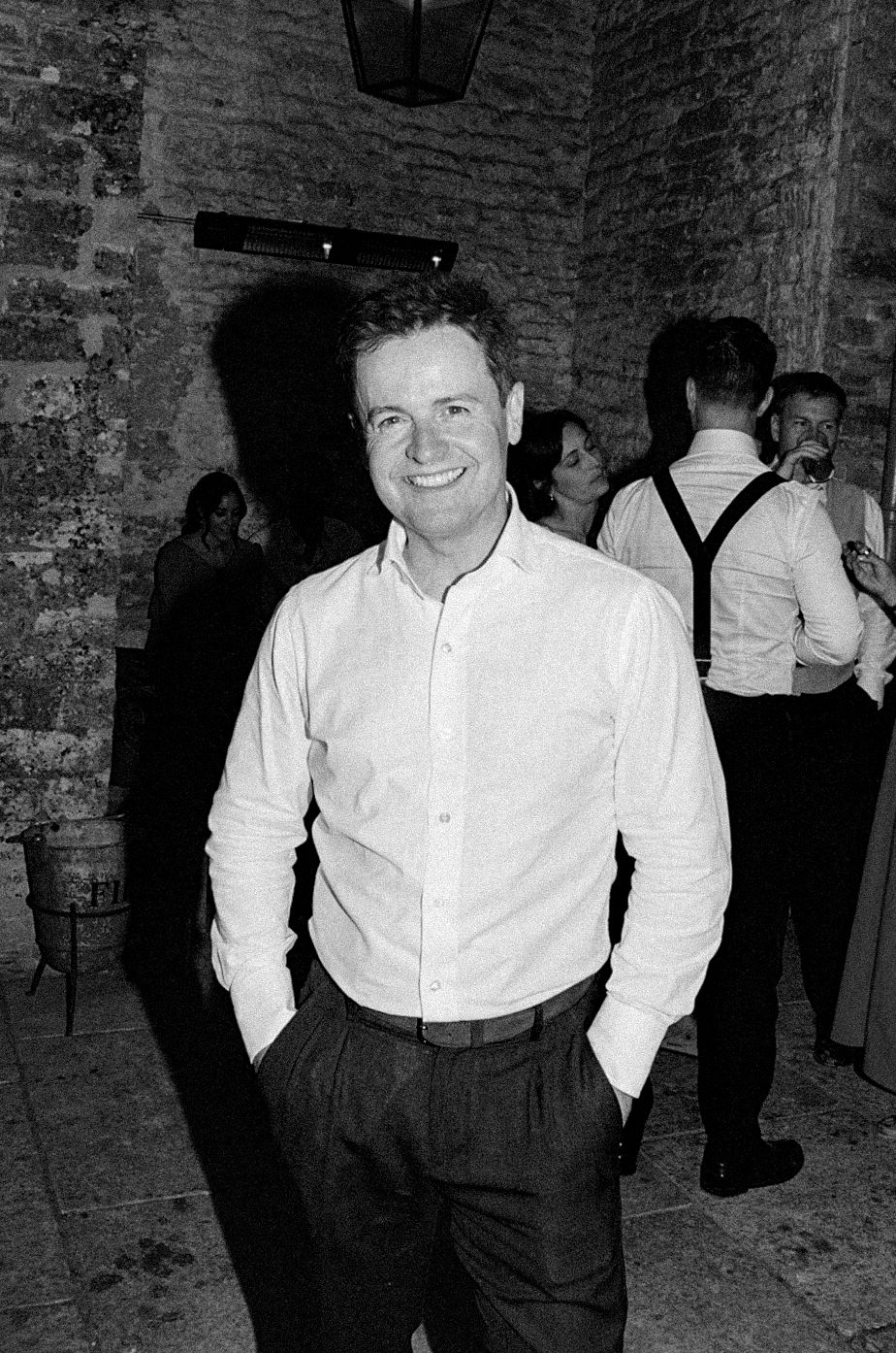 Smiling man in white shirt at elegant stone venue party, black and white photo.