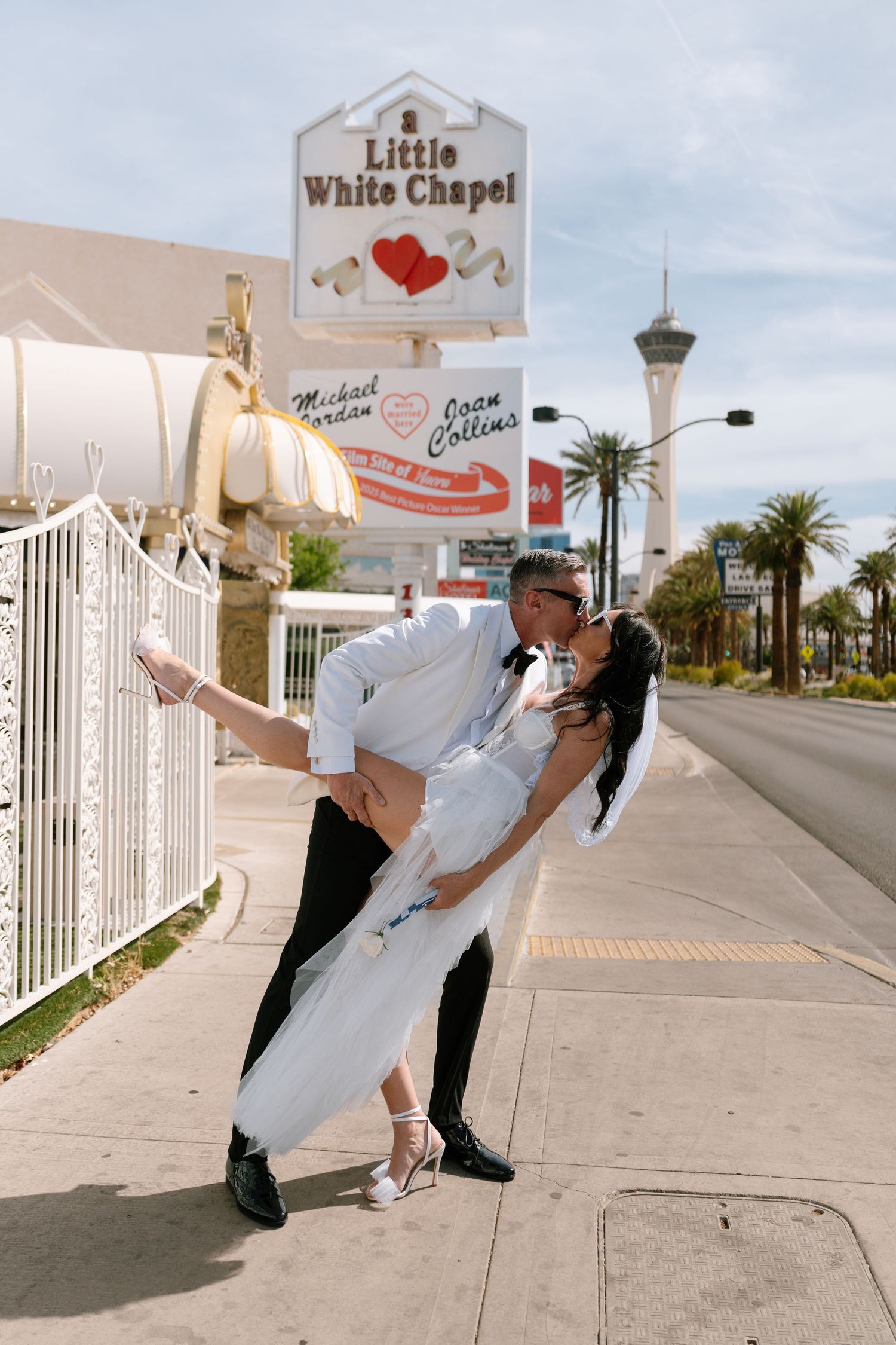 Newlyweds strike dramatic dance poses on sidewalk outside Las Vegas wedding chapel.