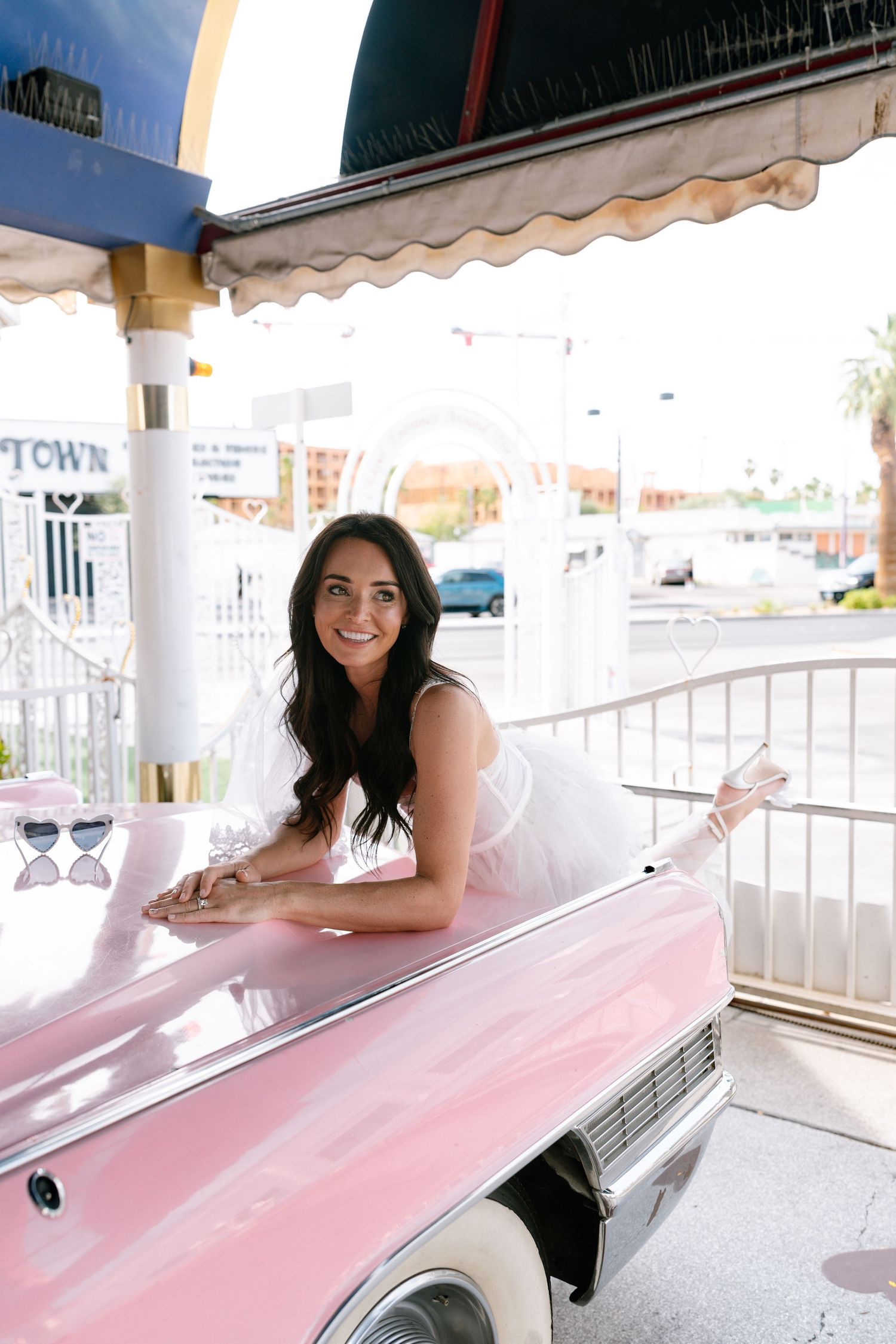 Candid moments captured with a vintage pink car at a wedding venue.