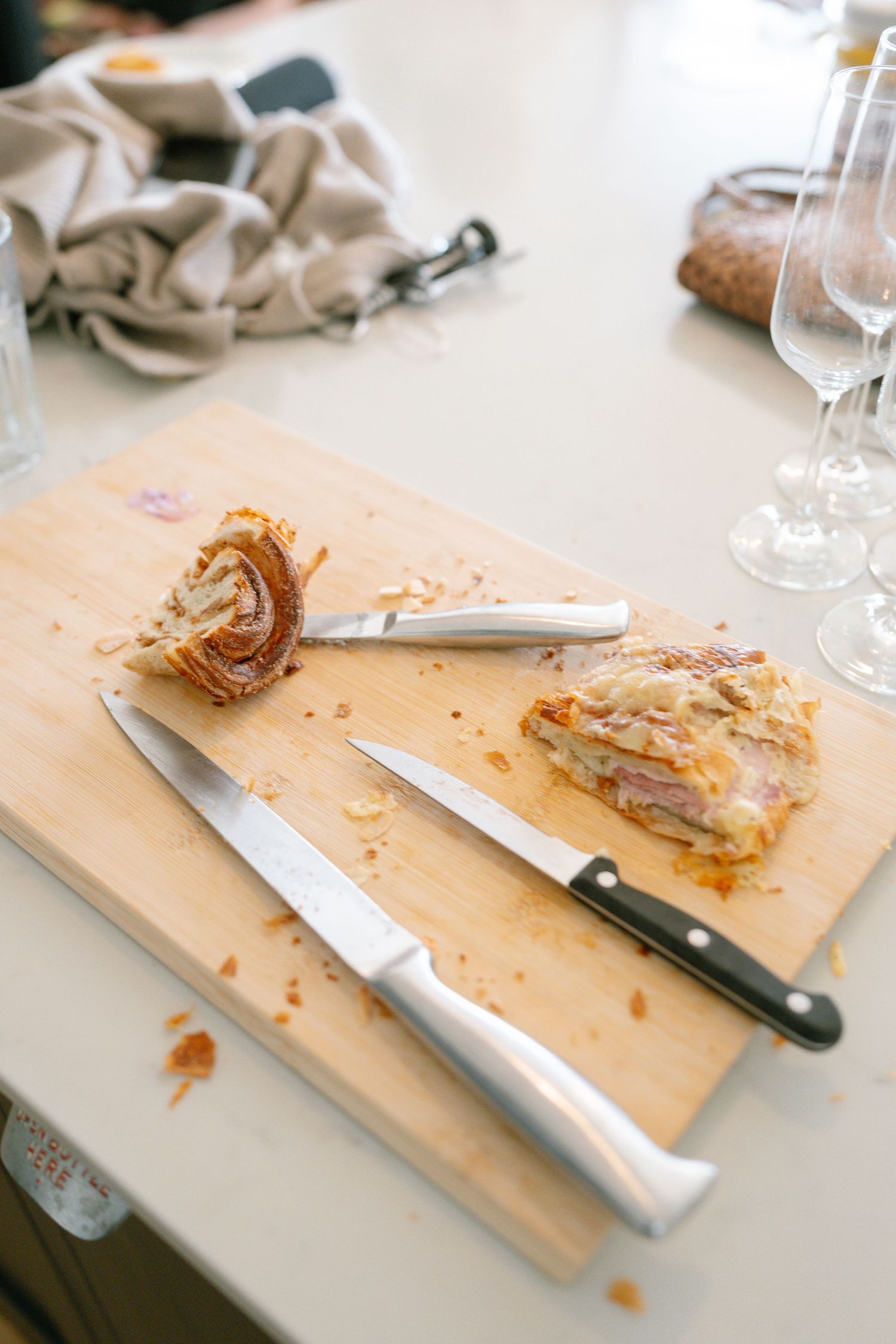 Wooden cutting board with knives and pastry crumbs showing signs of recent food preparation.