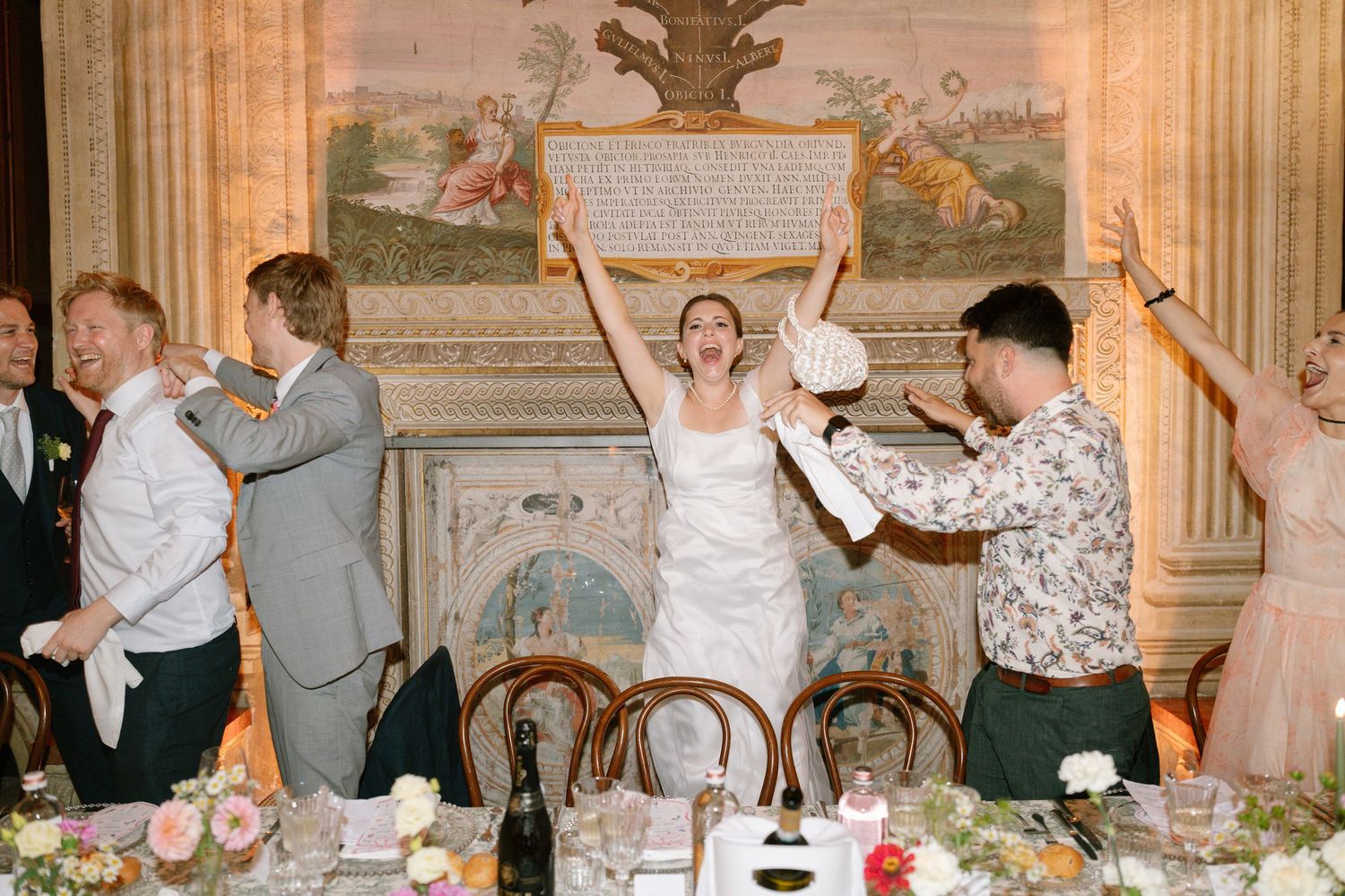 Vintage-style reception scene showing guests celebrating in a grand ballroom with classical decor.