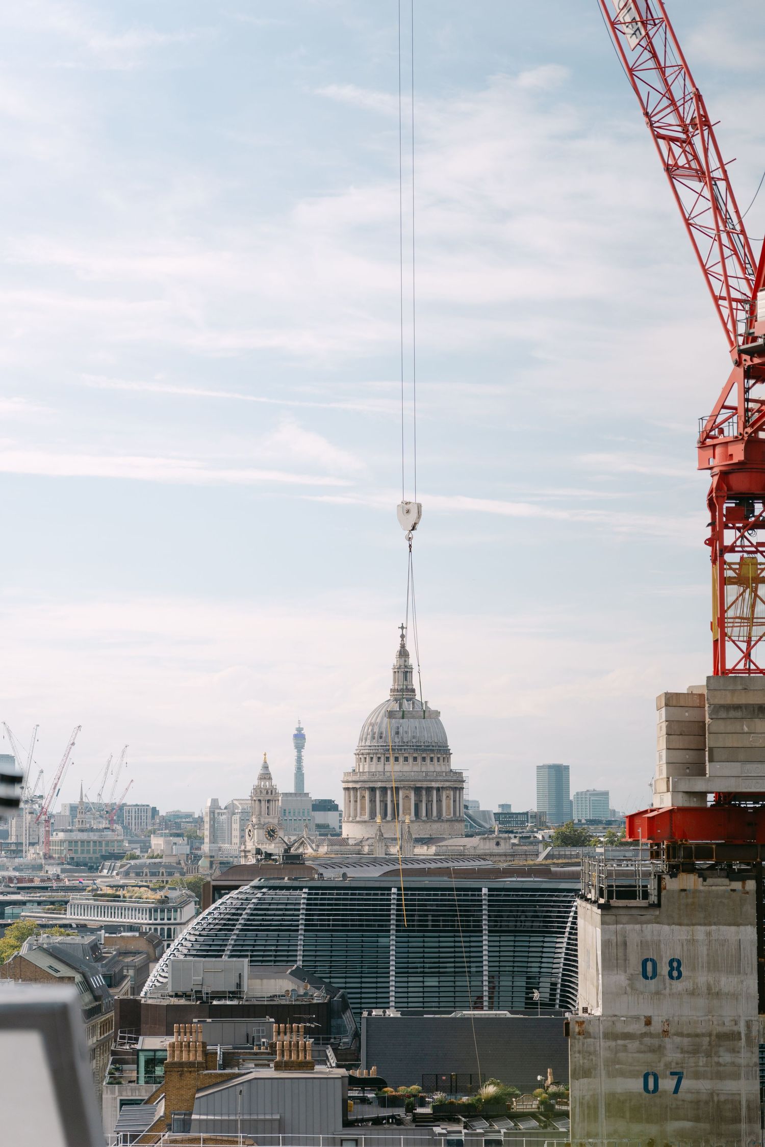 London cityscape with St Paul's Cathedral and construction cranes against blue sky.