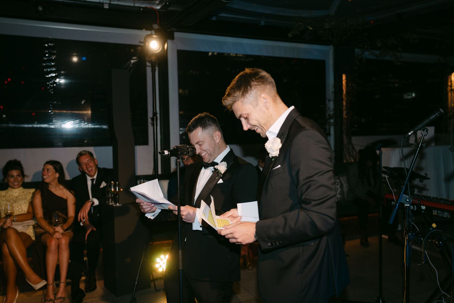 People gathered at a dark reception venue with hanging lights.