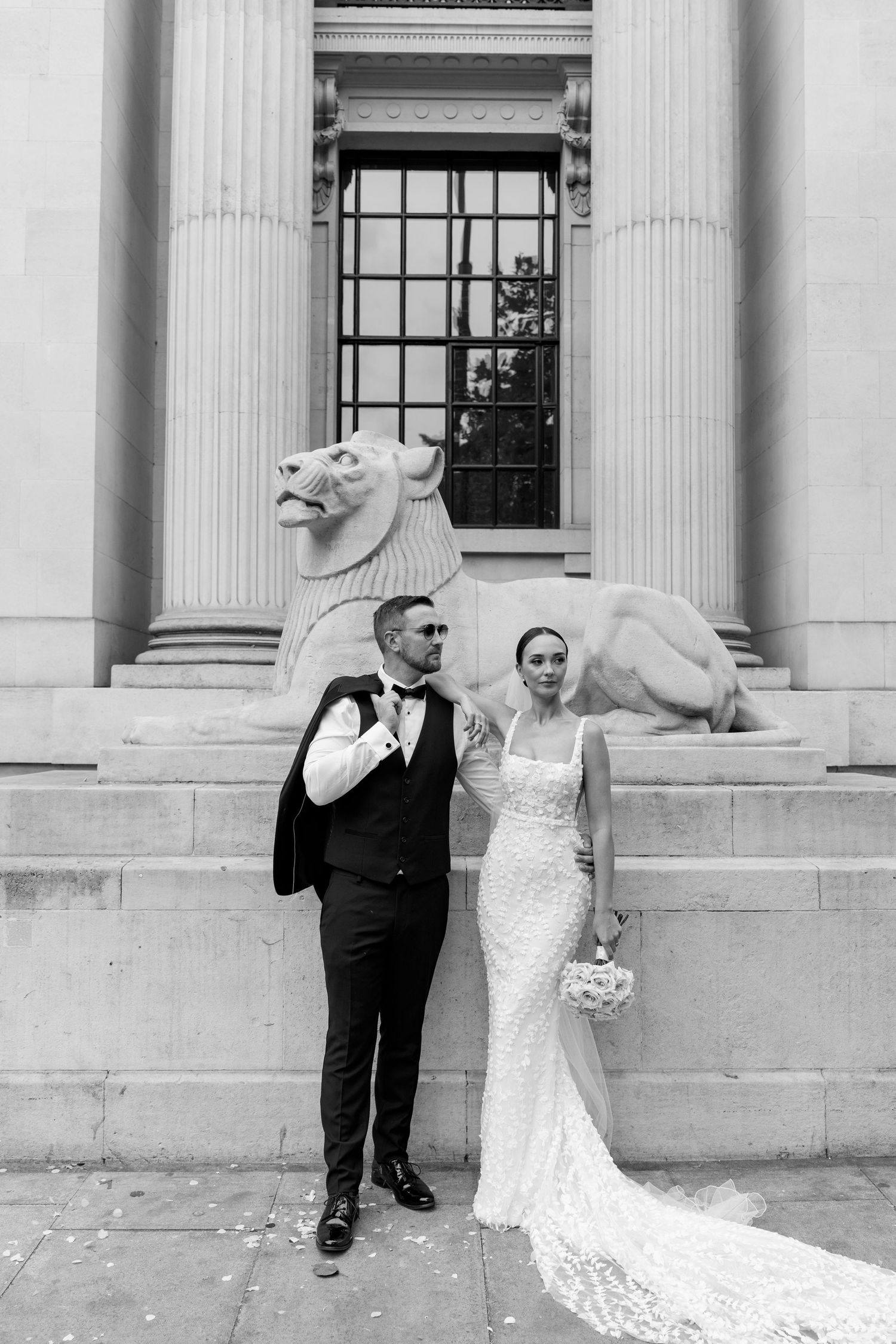Black and white wedding portraits taken against a neoclassical building facade.