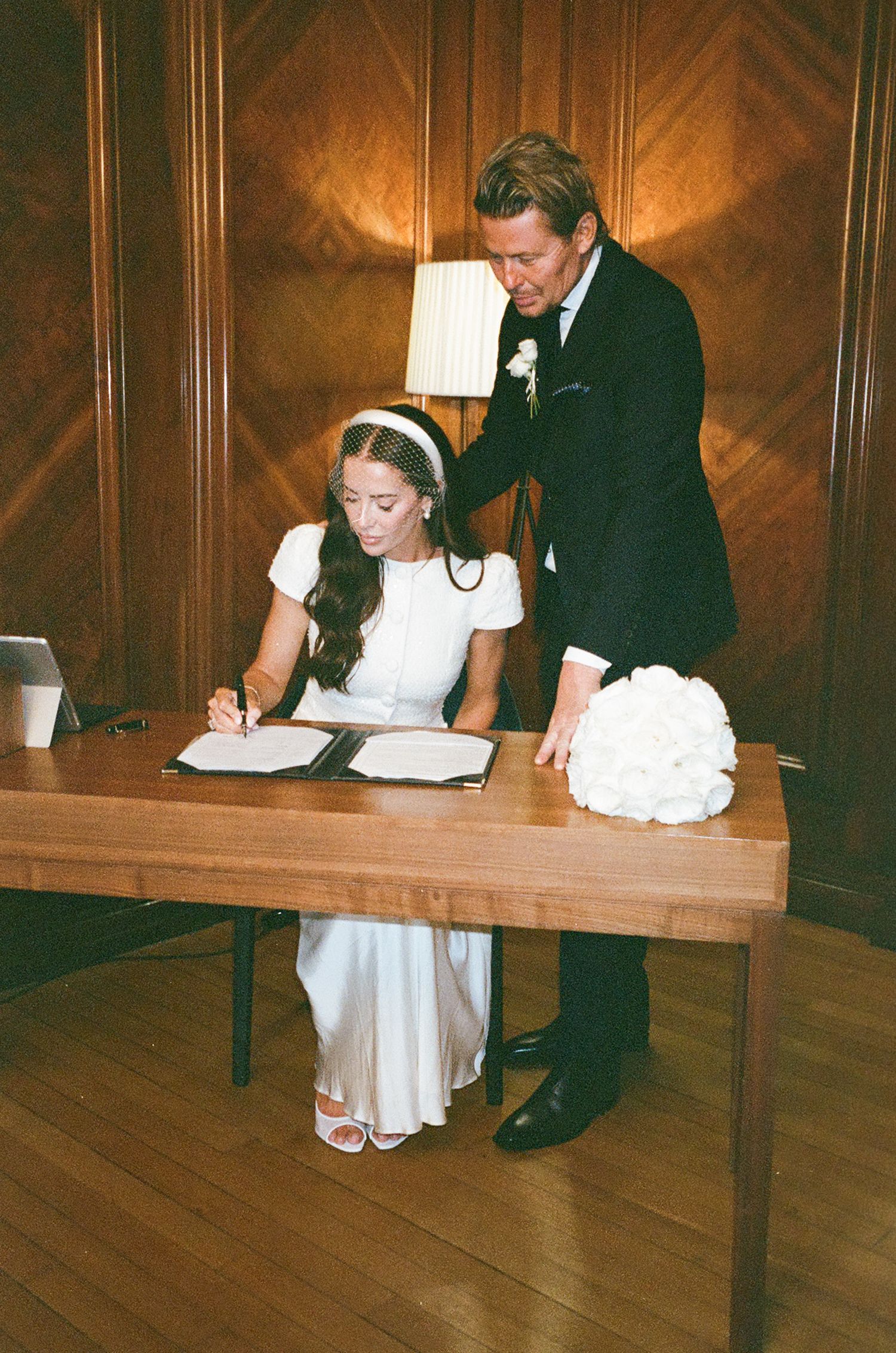 A series of photos showing a bride and groom signing marriage documents at a wooden table during their wedding ceremony.