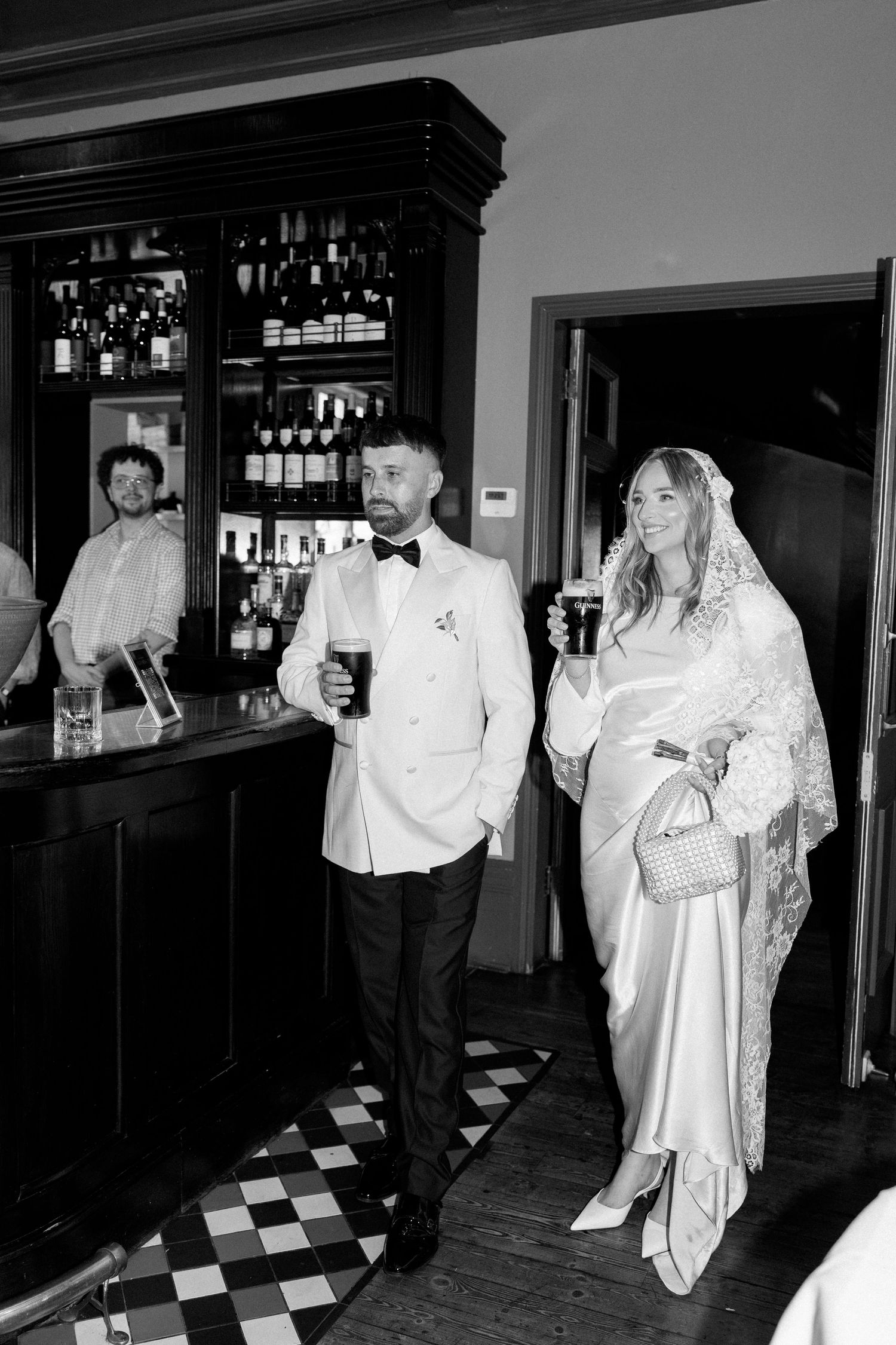 Wedding couple celebrates in a bar with black and white checkered floor.