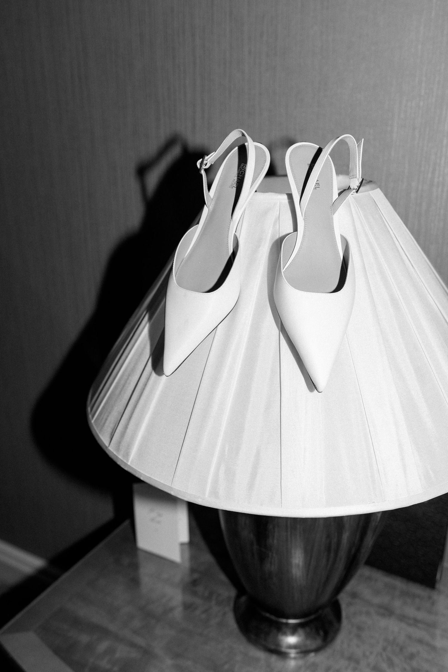 A sequence of black and white photos showing a white paper lamp shade being assembled on a dark base.