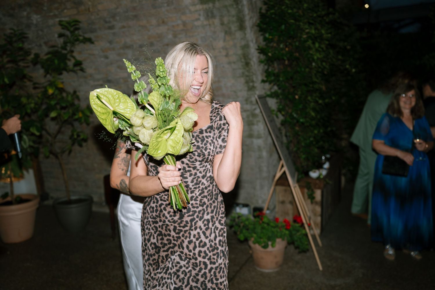 Outdoor wedding reception with guests gathered in a garden setting.