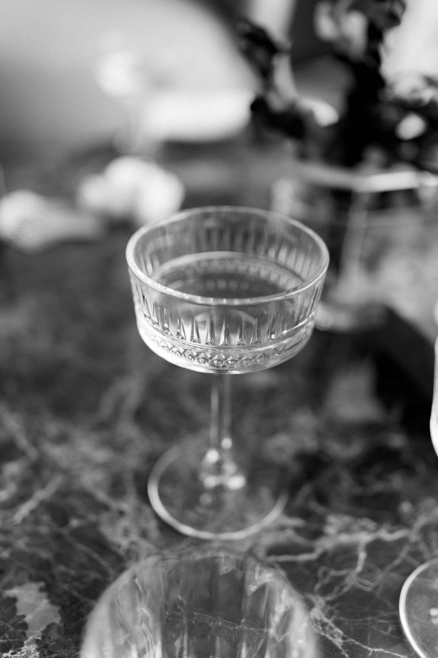 Elegant crystal coupe glass with cocktail on marble surface in black and white.