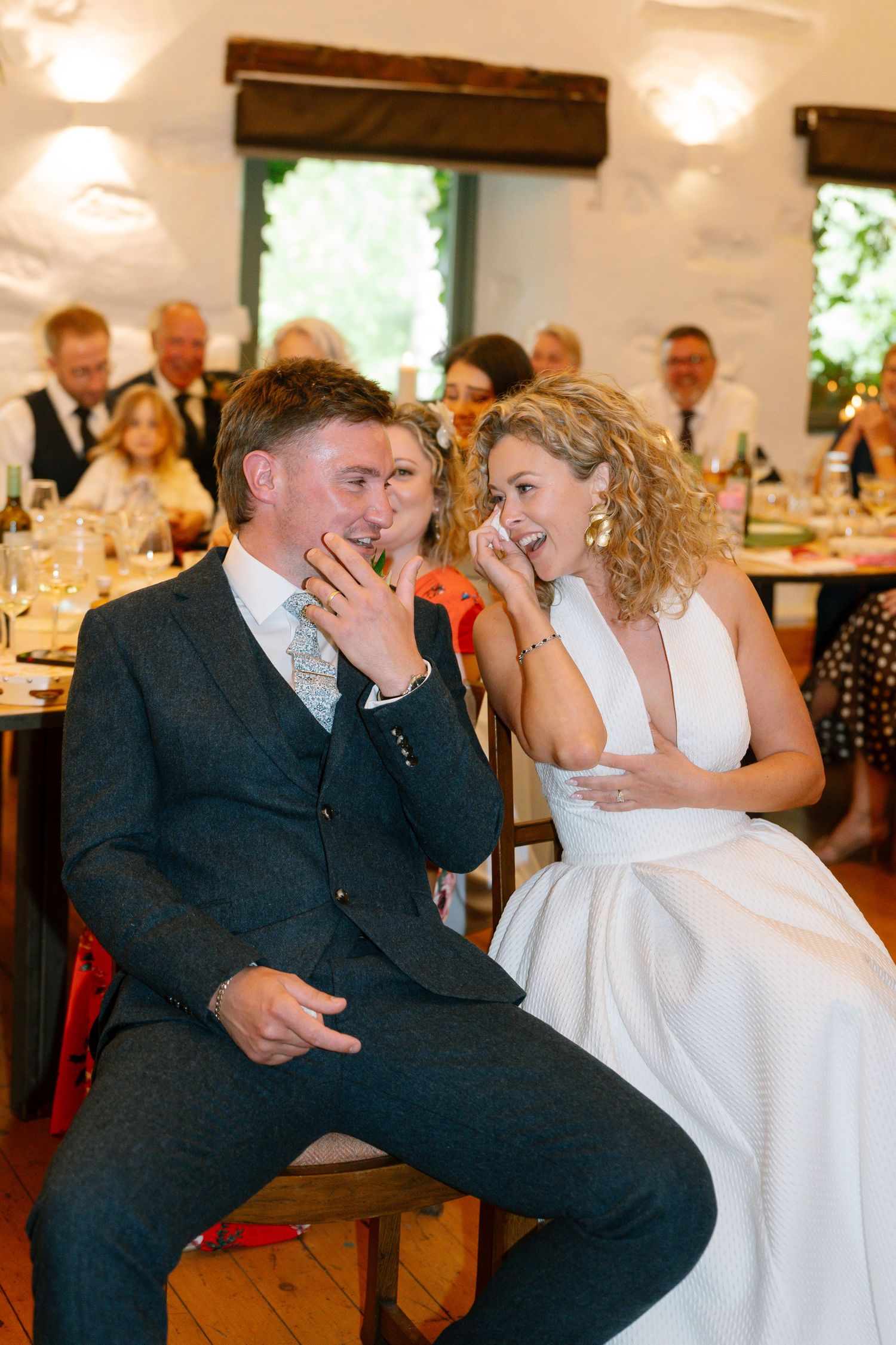 Couple shares a candid laughing moment during their wedding reception.