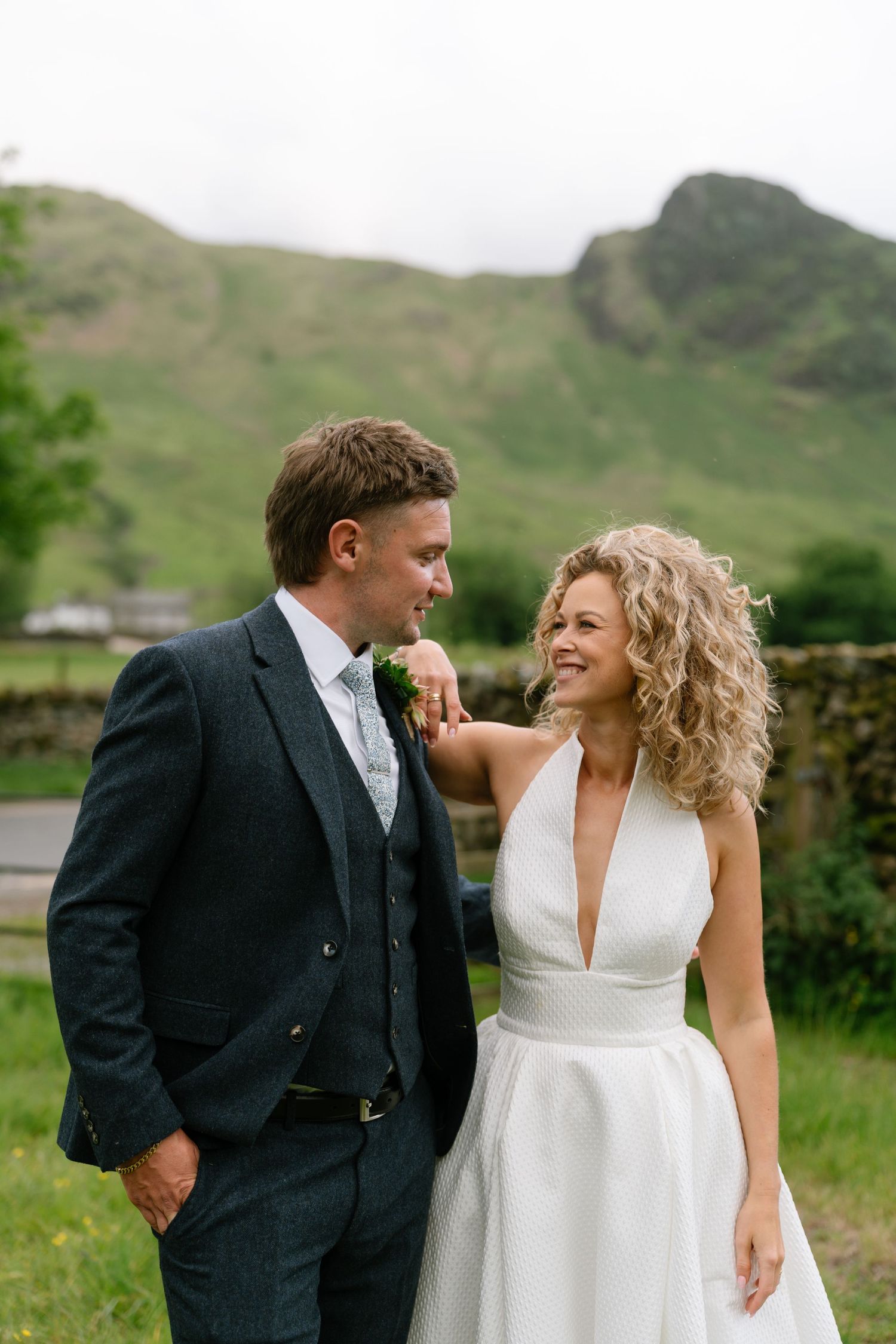 Candid wedding portrait against scenic mountain backdrop with stone walls.